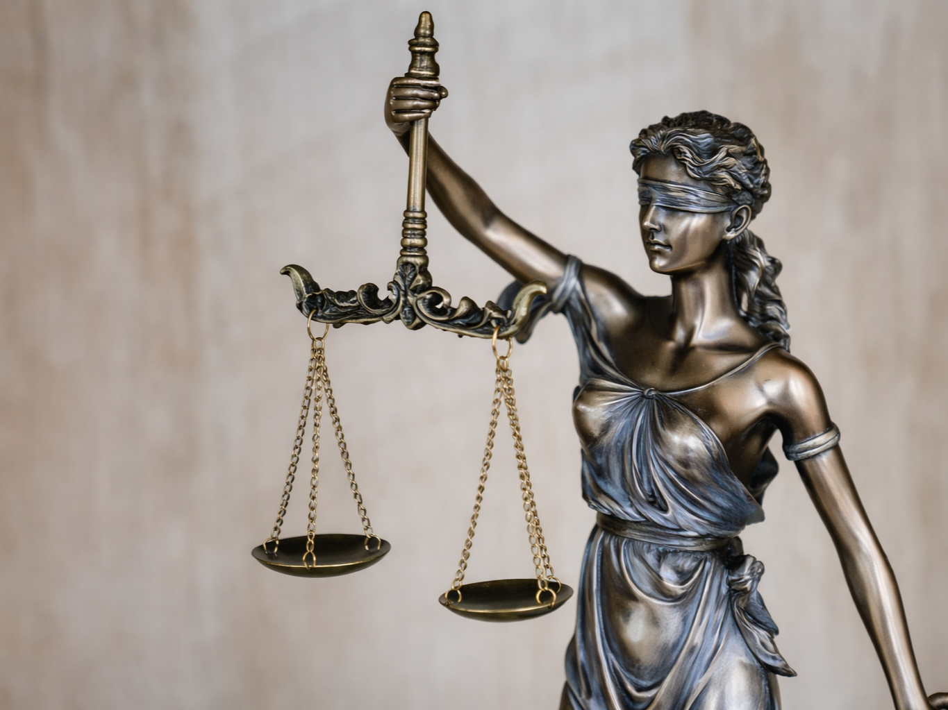 Escultura de la diosa de la justicia con los ojos vendados, sosteniendo una balanza.