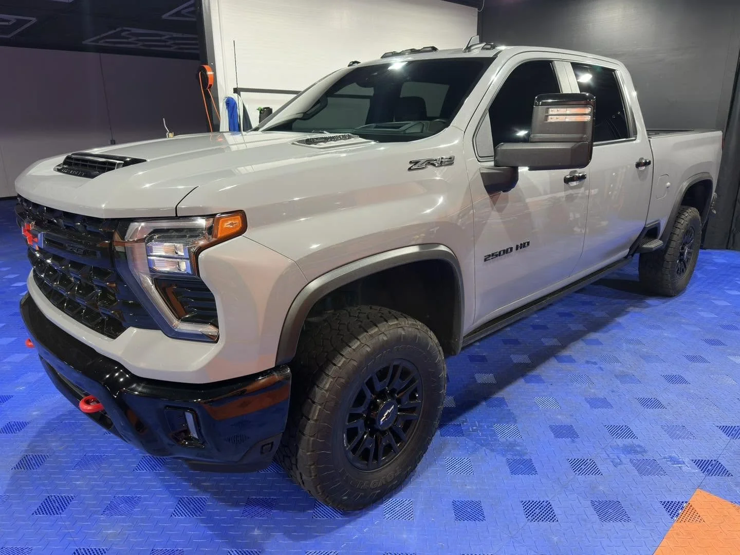 A white Chevrolet Silverado ZR2 pickup truck displayed on a blue floor in an indoor showroom.