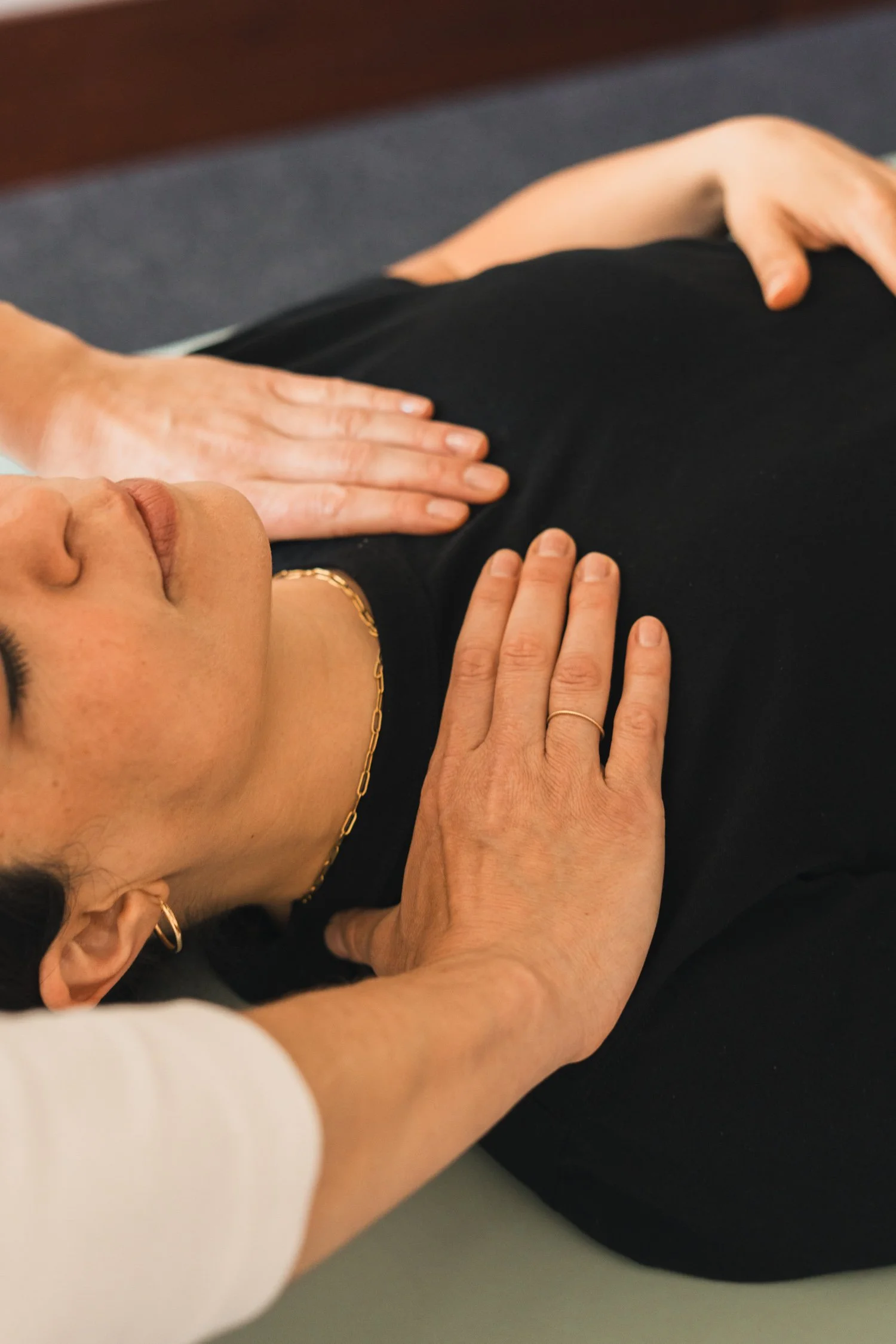 A person lying on their side on a massage table while another person provides a massage. The person receiving the massage appears relaxed.