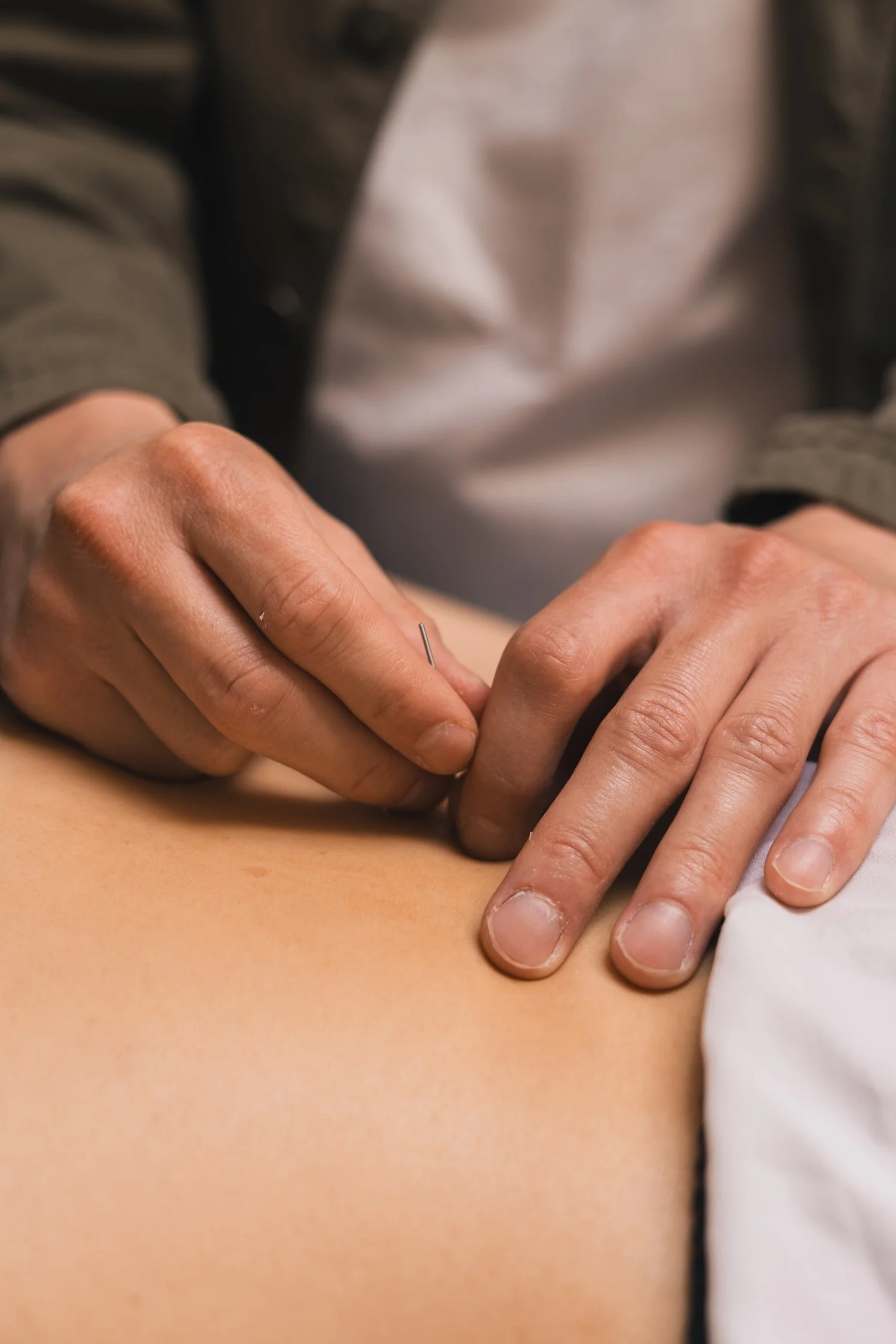 A person receiving a medical injection in their upper arm, with a healthcare professional administering the shot using a needle.