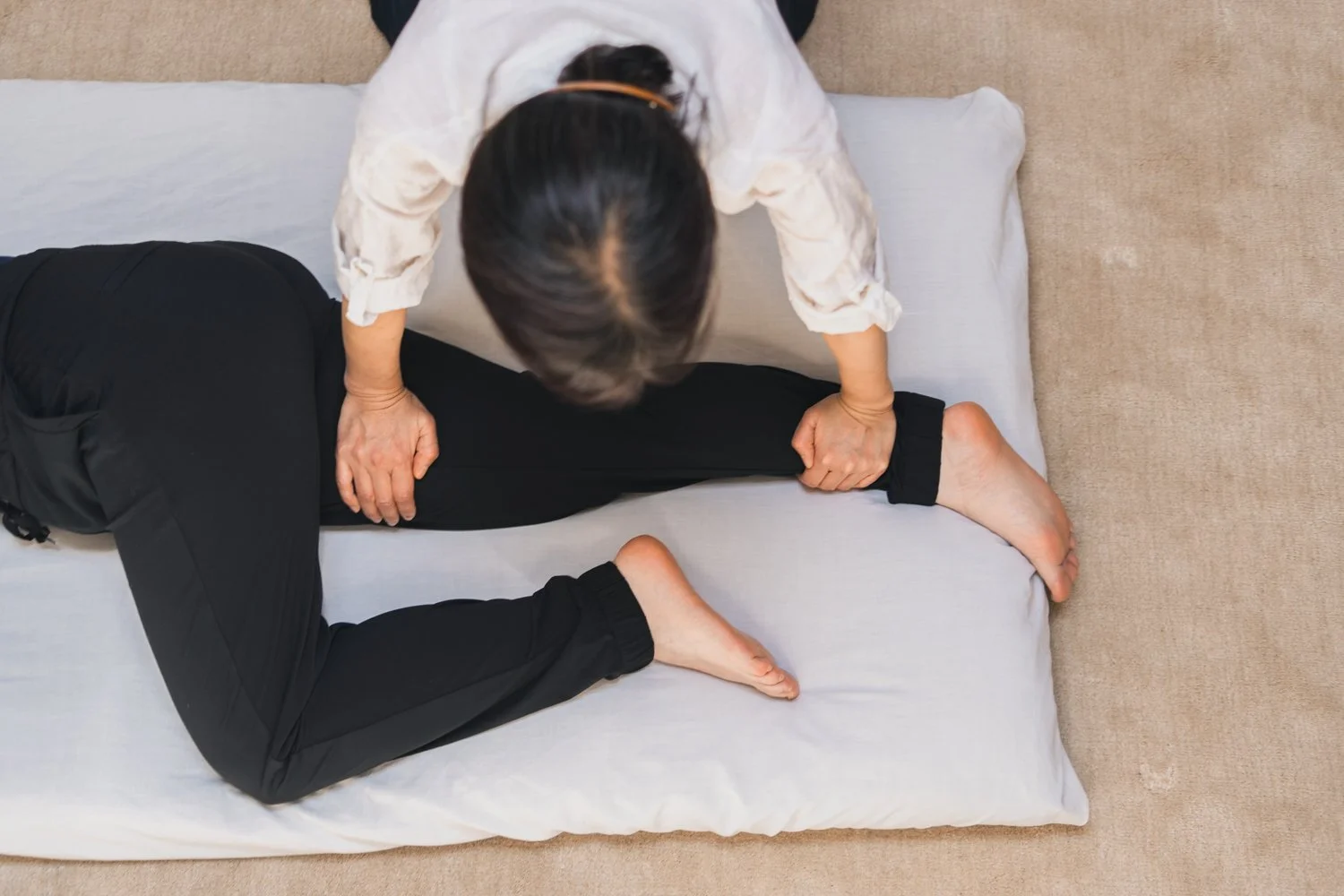 A person receiving a massage or physical therapy on their leg, lying on a padded surface.