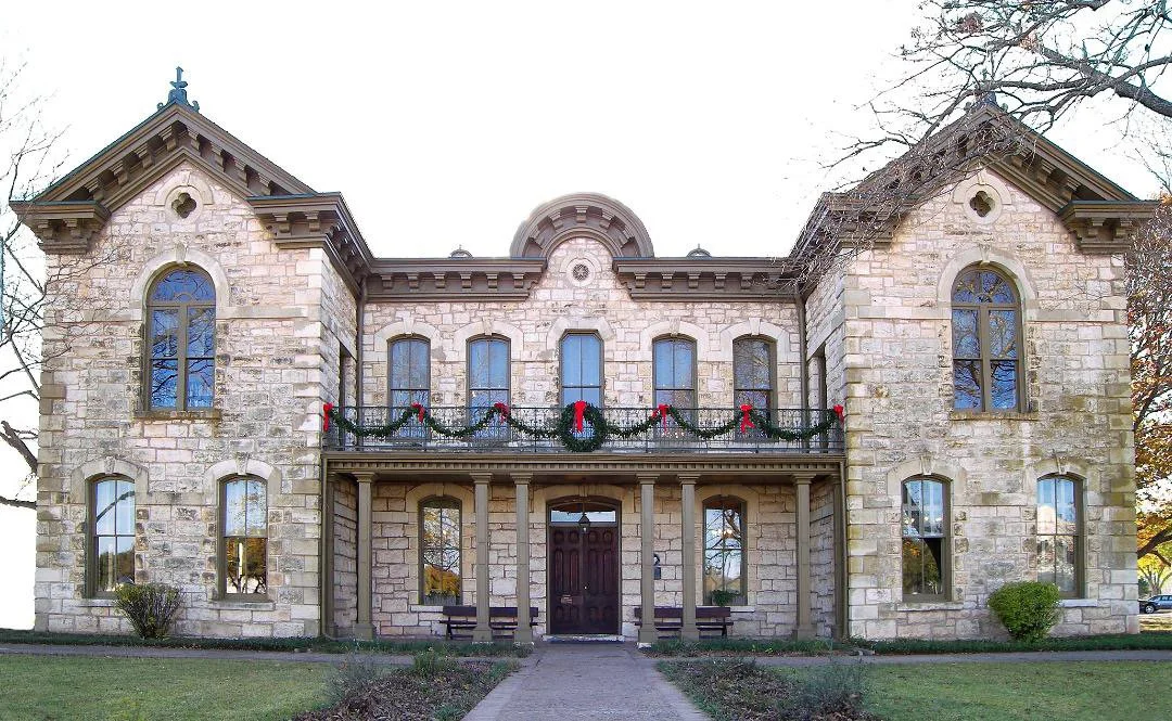 A historic stone mansion decorated with Christmas wreaths and garlands.