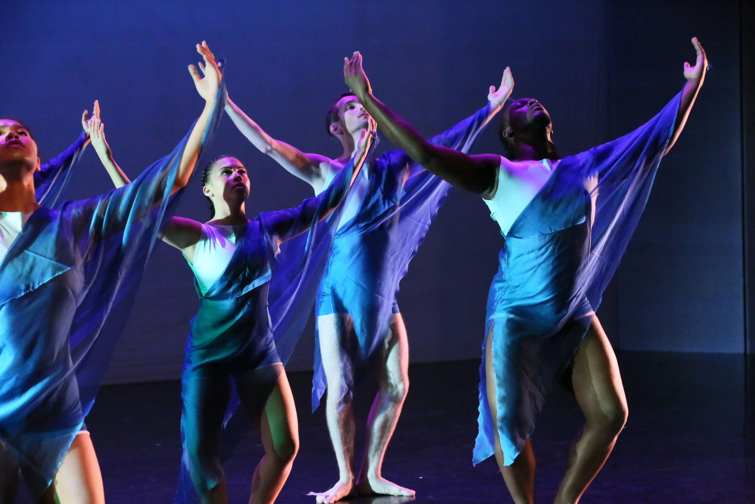 Dance performance with multiple dancers in flowing costumes on stage