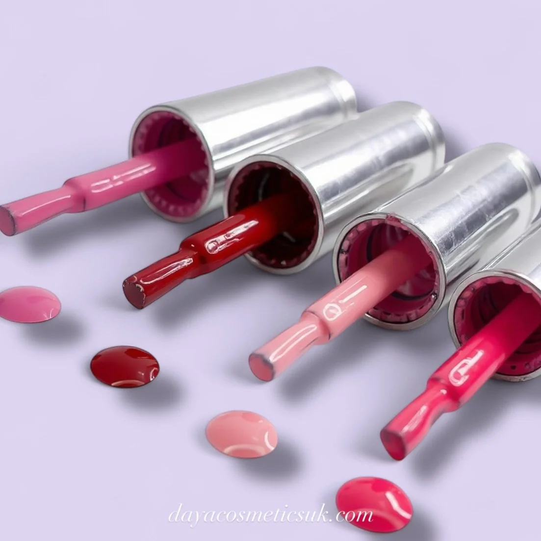 Four tubes of nail polish in various shades of pink and red, with some spilled on a light-colored surface