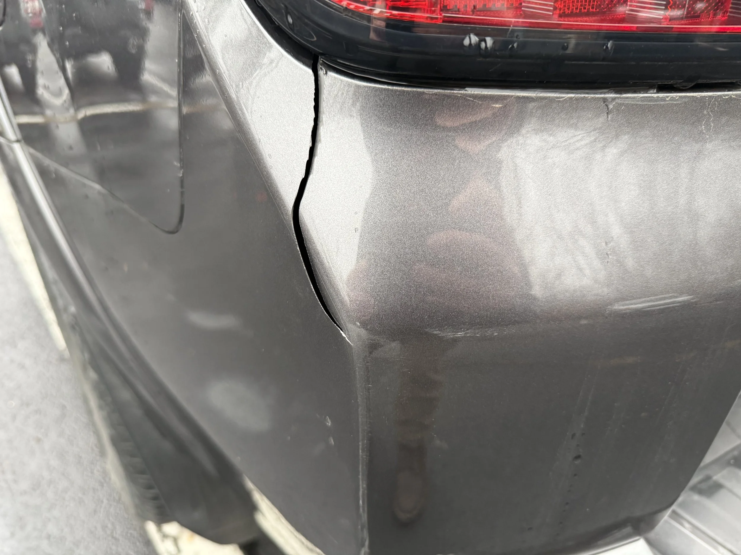 Close-up of a black car with a visible crack on the rear bumper.