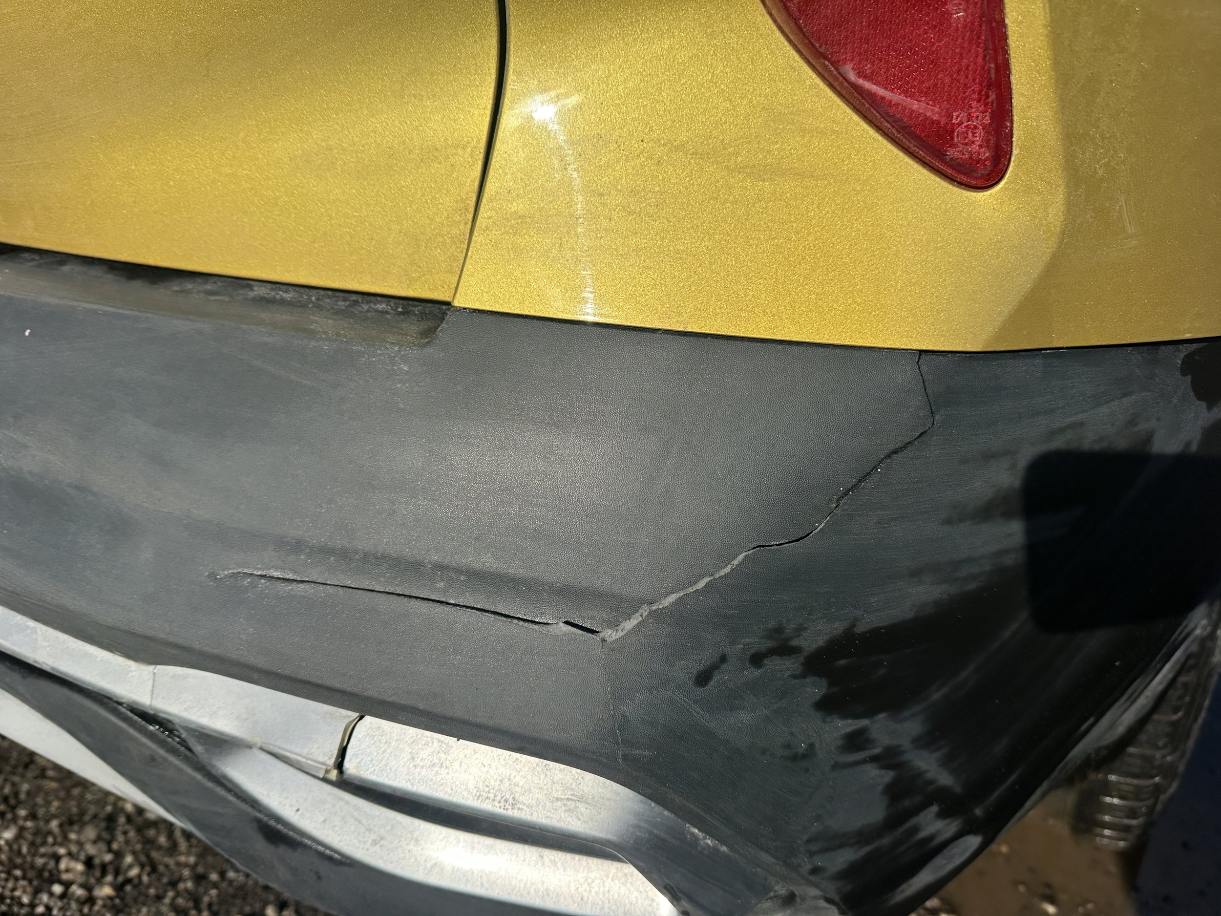 Crack on black bumper of a yellow car.