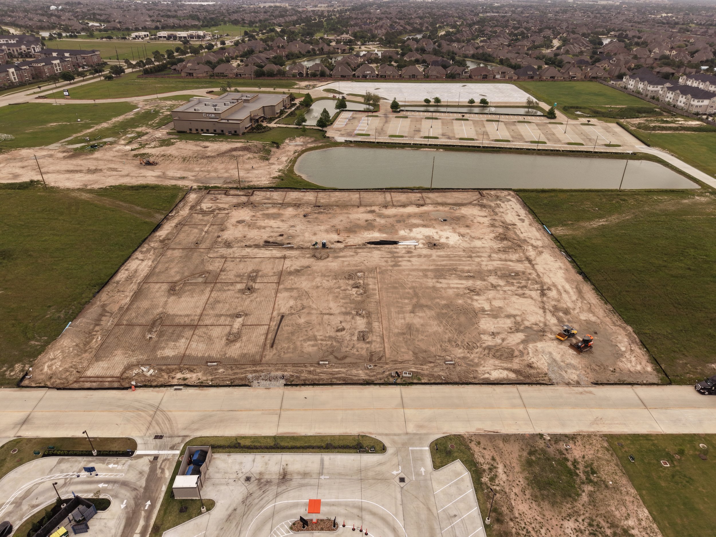 Oblique aerial view of a construction site in Cypress, TX, showing surrounding roads and buildings