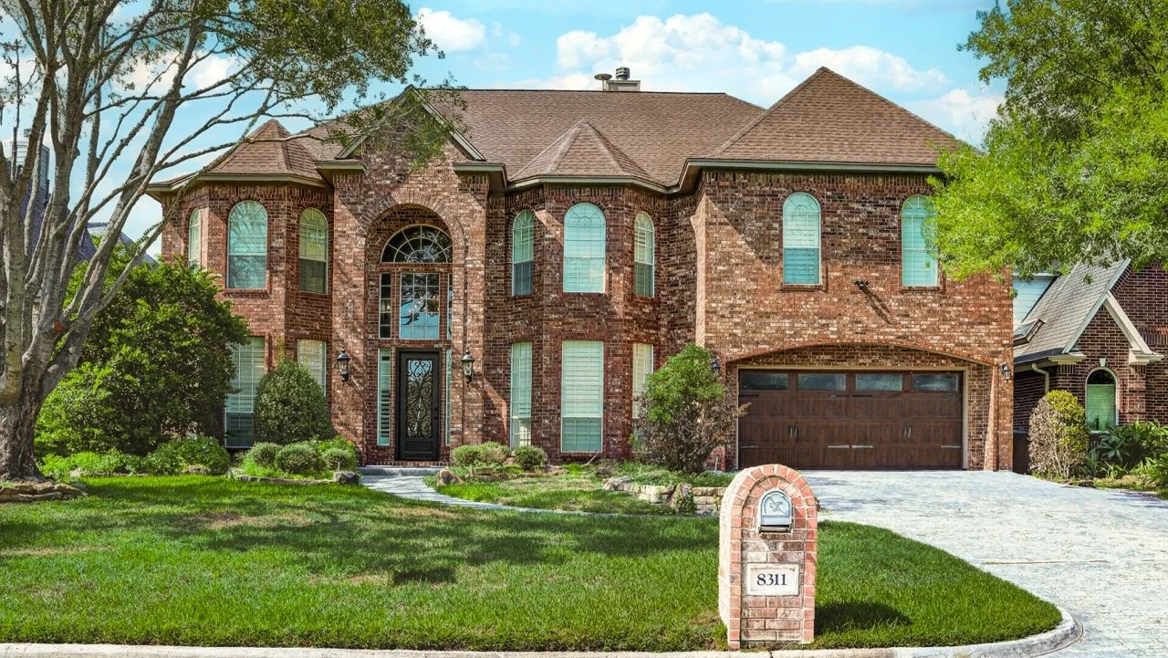 Two story brick home with a manicured front lawn in Atascocita, TX