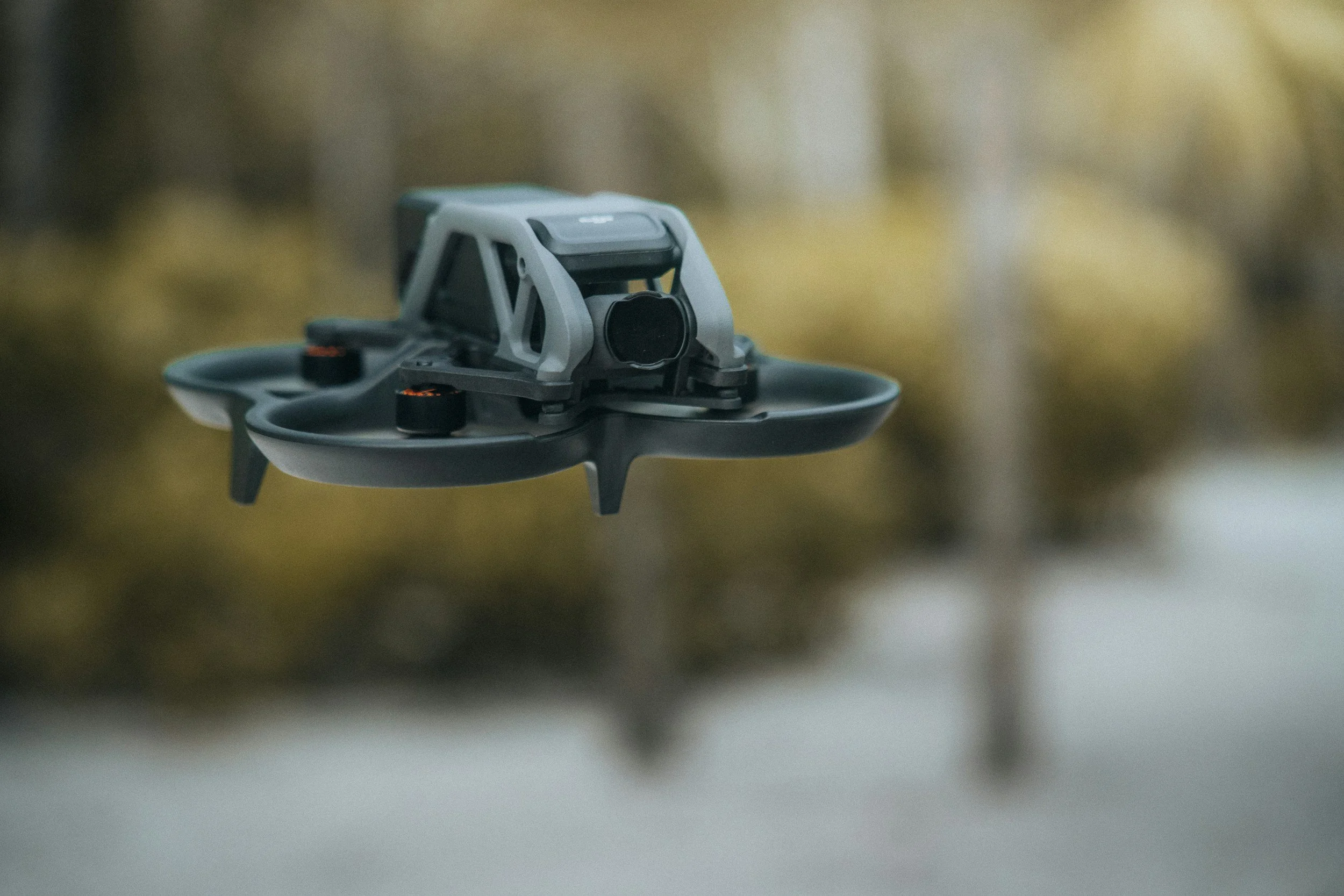 Close-up of a drone hovering outdoors with a blurred background.