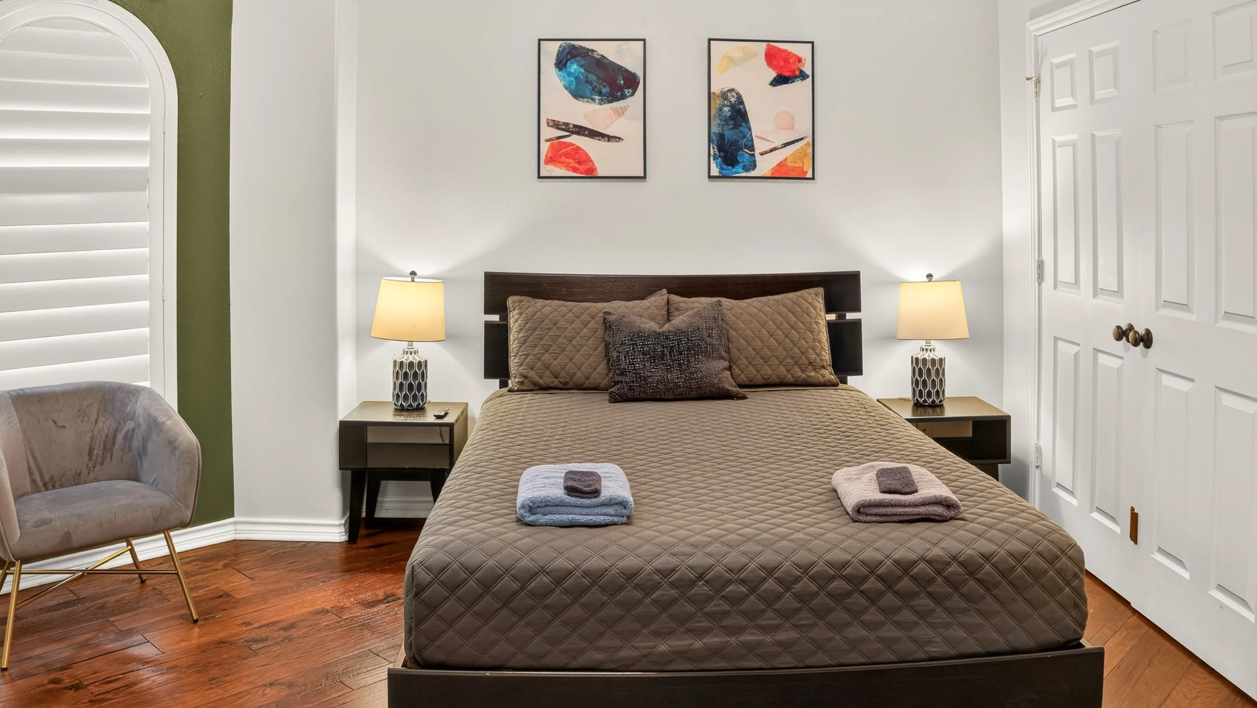 Bedroom with a dark bedspread and colorful wall art