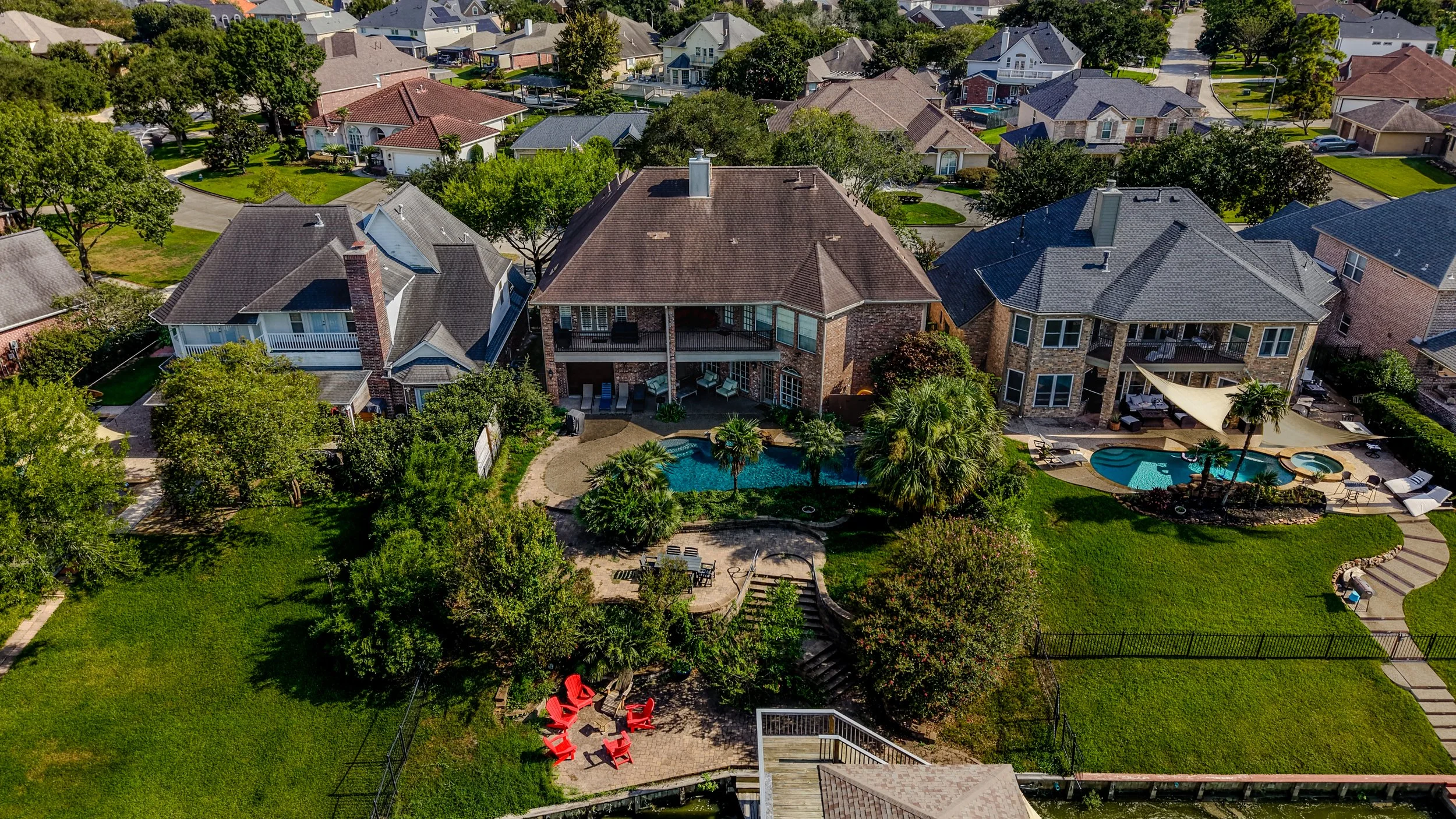 Aerial view of the home and backyard surrounded by mature trees