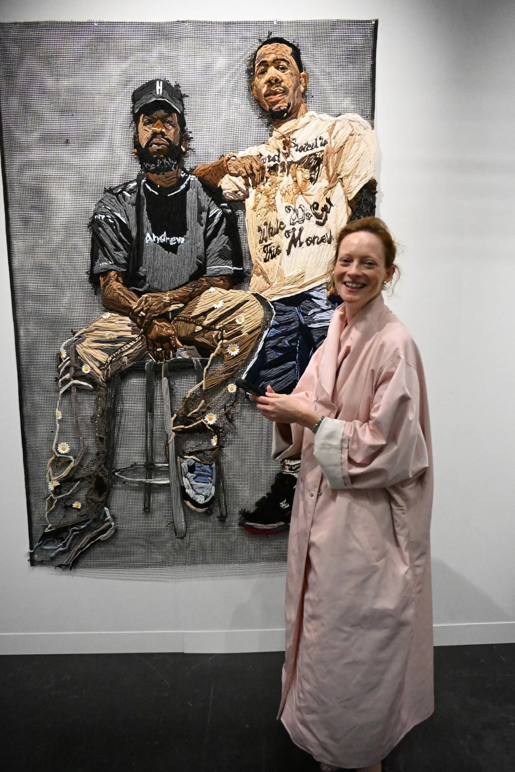 Model Margarita at ACA Galleries, with Kandy G Lopez's large fiber portrait R² - Roscoe and Reggie (2024), booth 124.