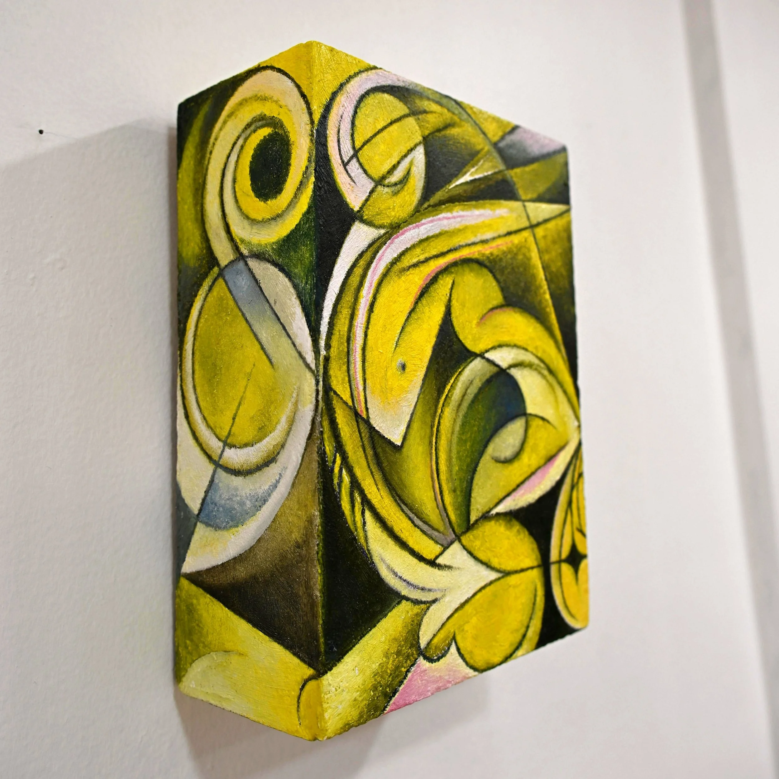 Close-up of a small, square, yellow and black abstract painting on a white wall.
