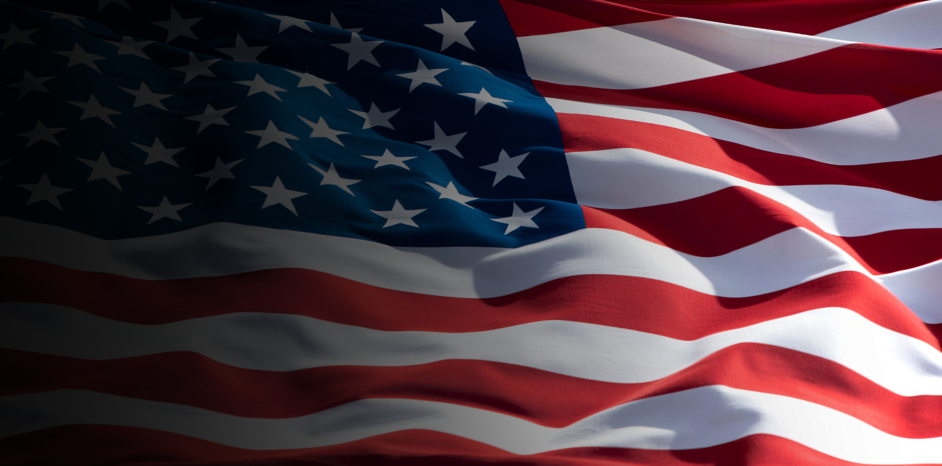 American flag waving with red and white stripes and white stars on a blue field.