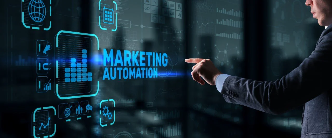 A person in a business suit pointing at a digital screen displaying icons and text about marketing automation.