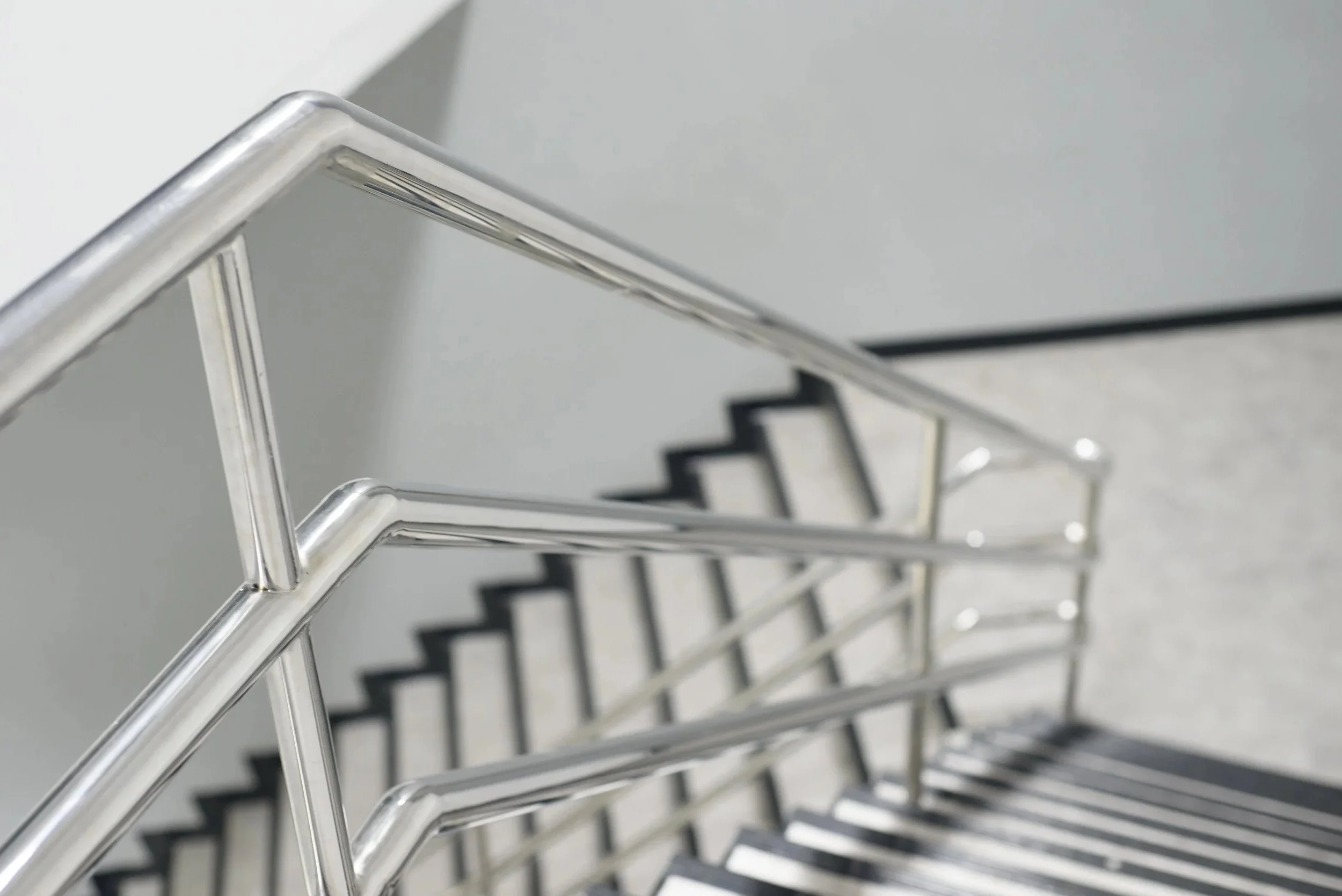 A top-down view of a metal staircase with steps made of black and white striped material.