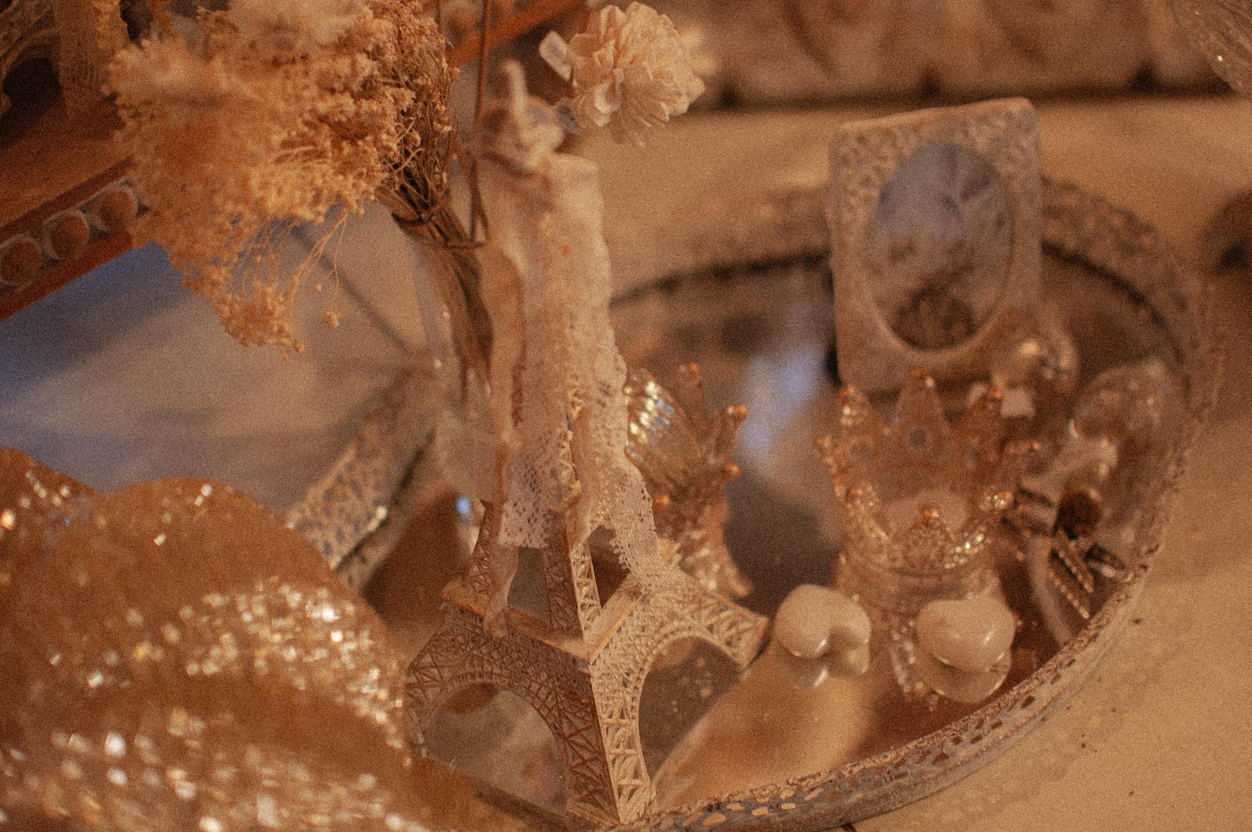 A collection of small decorative items resembling Paris landmarks, including a miniature Eiffel Tower, arranged on a tray with dried flowers.