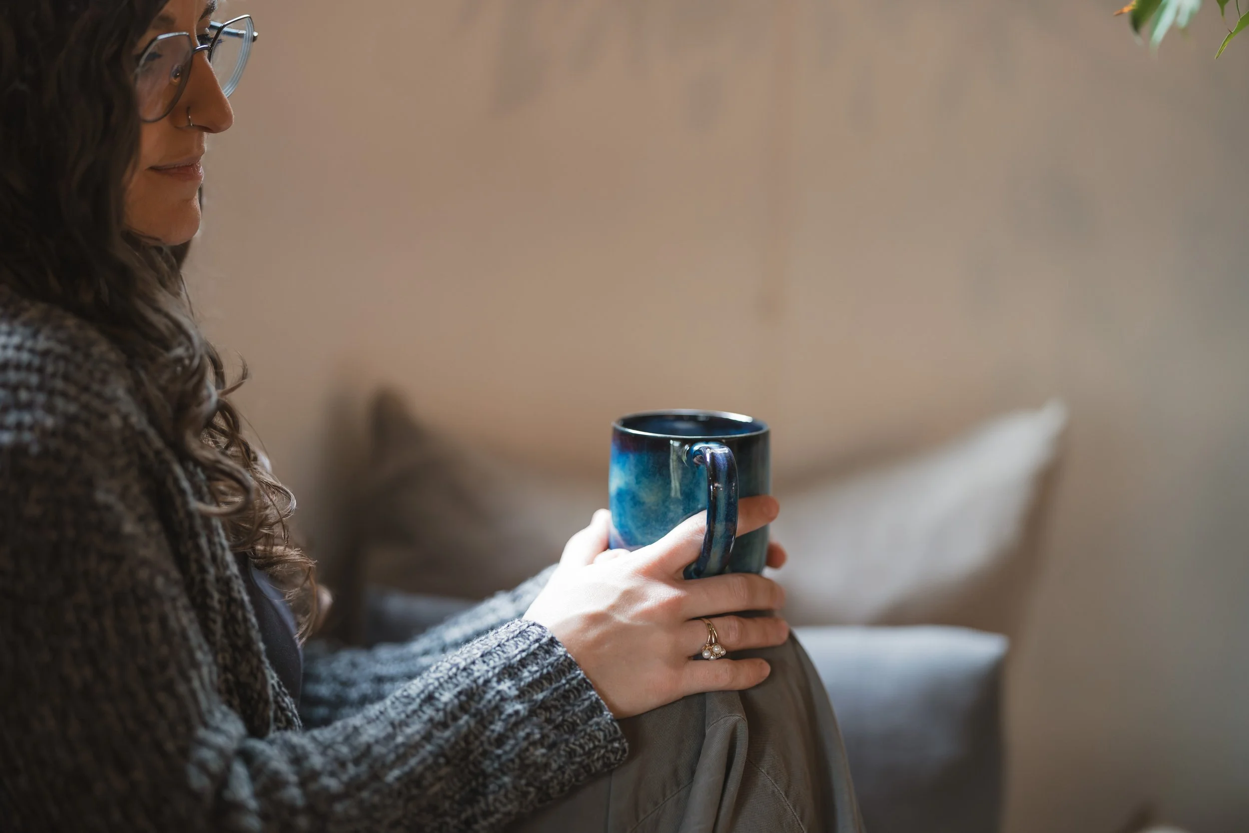 woman sitting by a window holding mug