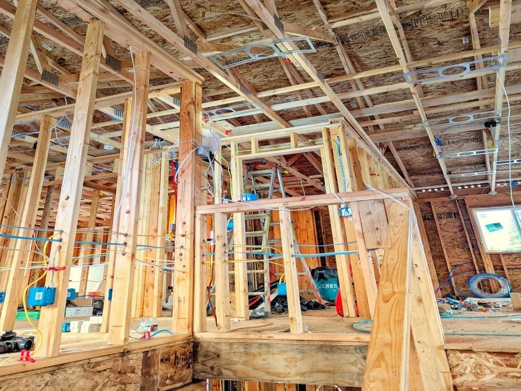 Current residential project at front door looking up to 2nd floor at exposed framing and electrical install. Ladder and tools in background. 
