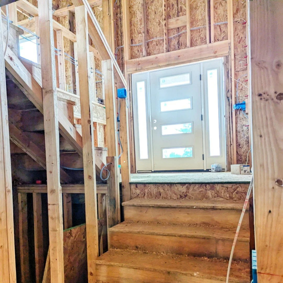 Sunlight shines thru front door windows on a current project. Lighting up exposed stairwell framework of a split level home.
