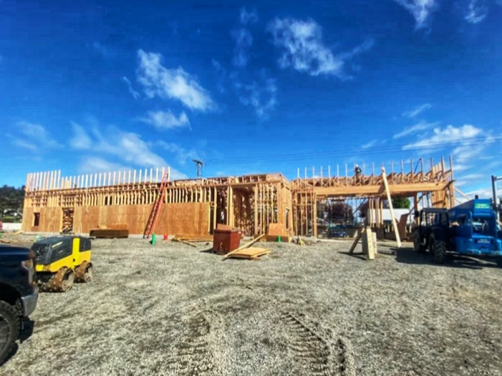 Commercial construction project during structural framing under a bright blue sky on a sunny day.