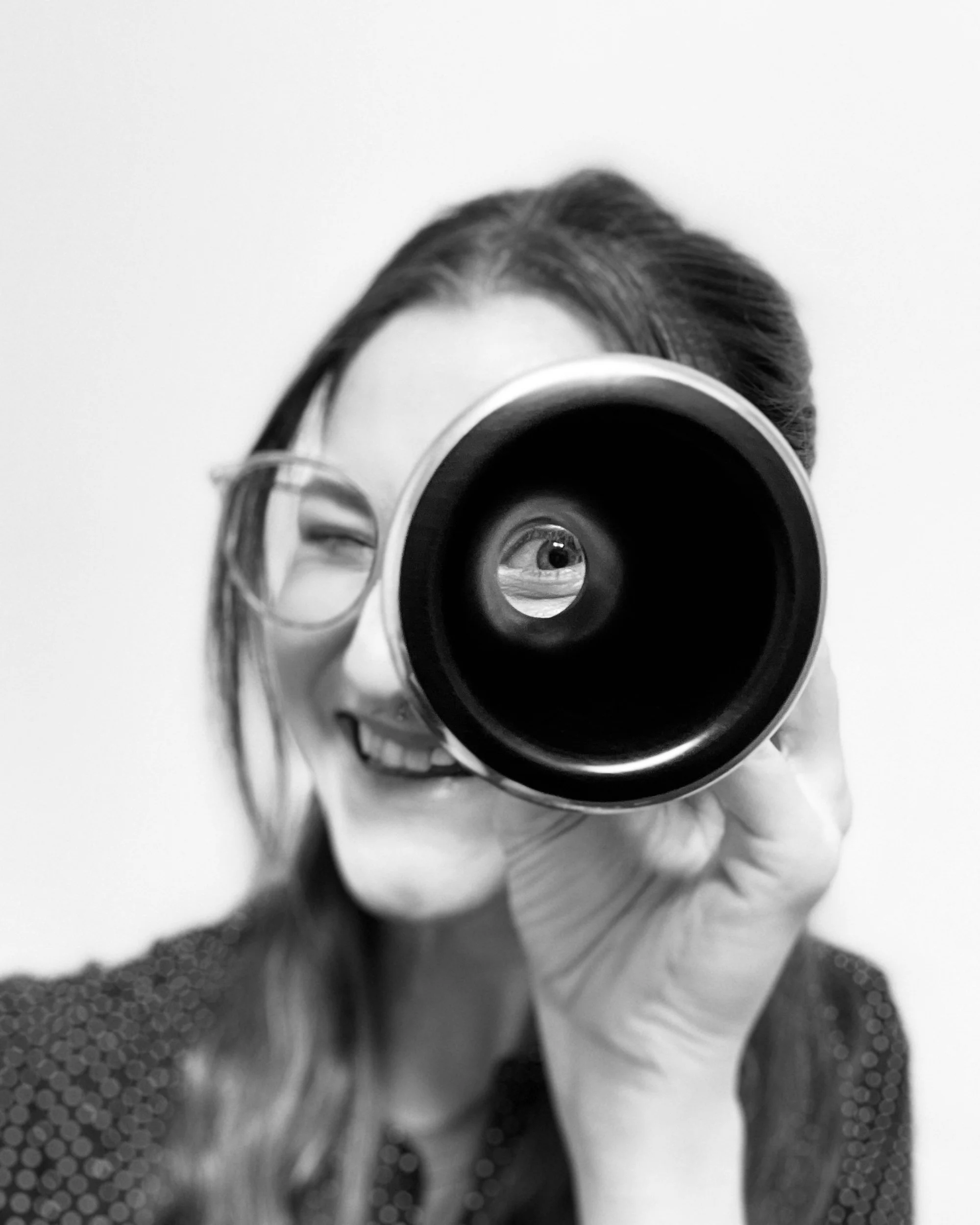 Photo of woman holding clarinet bell to one eye and looking through it like a telescope