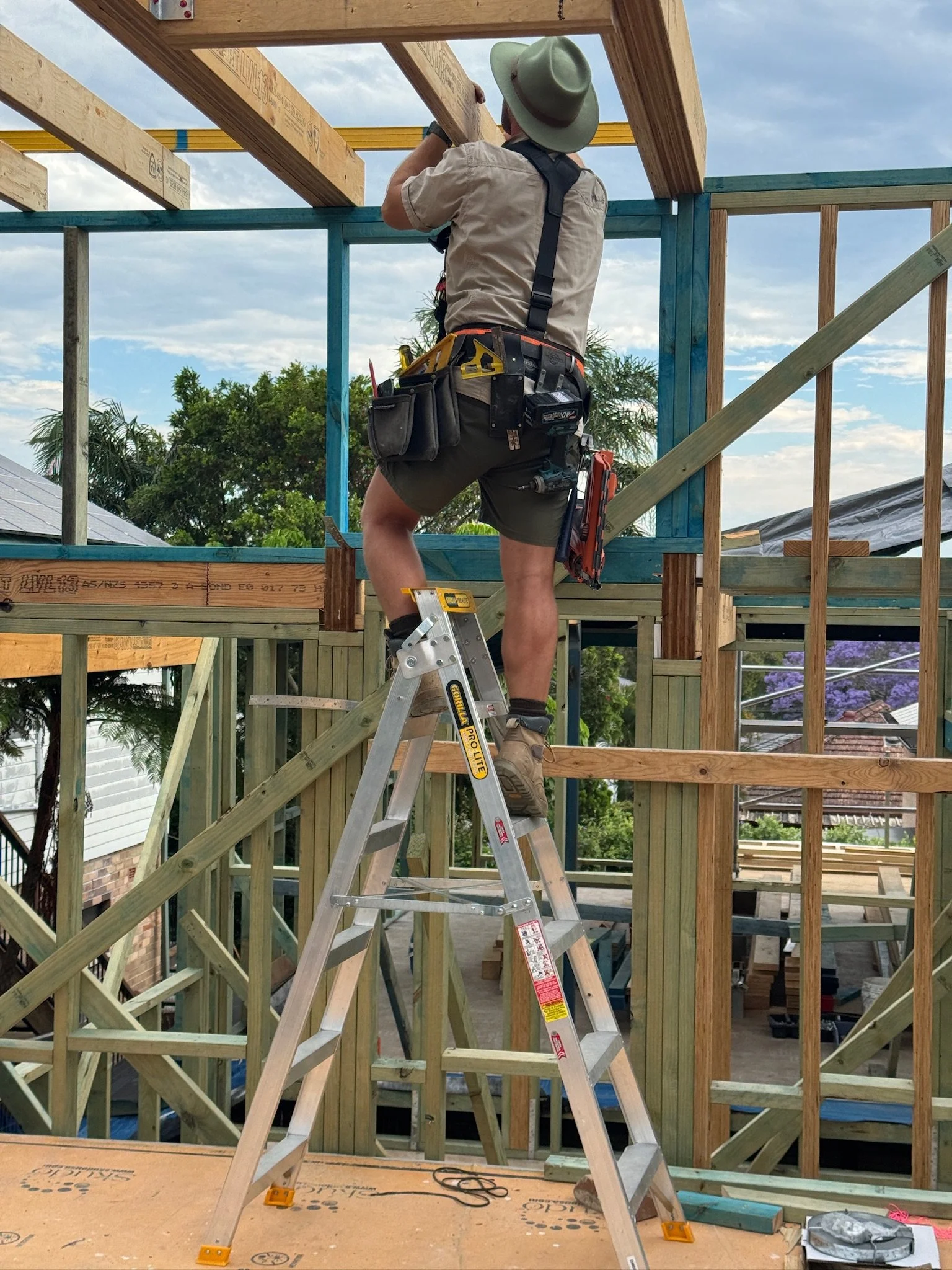 Carpenter man up a ladder building framing