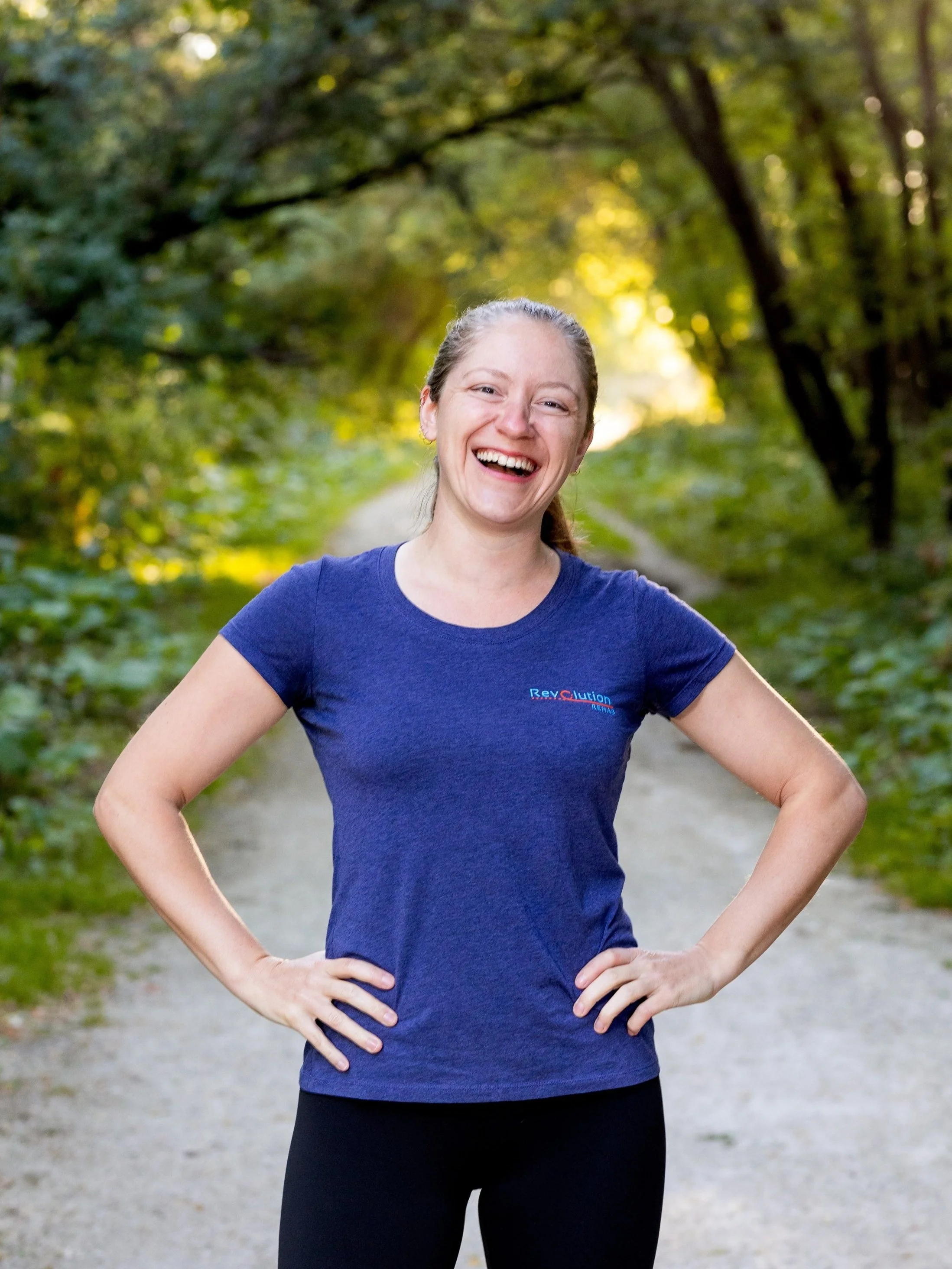 Owner Nikki Smith, Certified Athletic Therapist standing outside with a smile wearing a Revolution Rehab top.