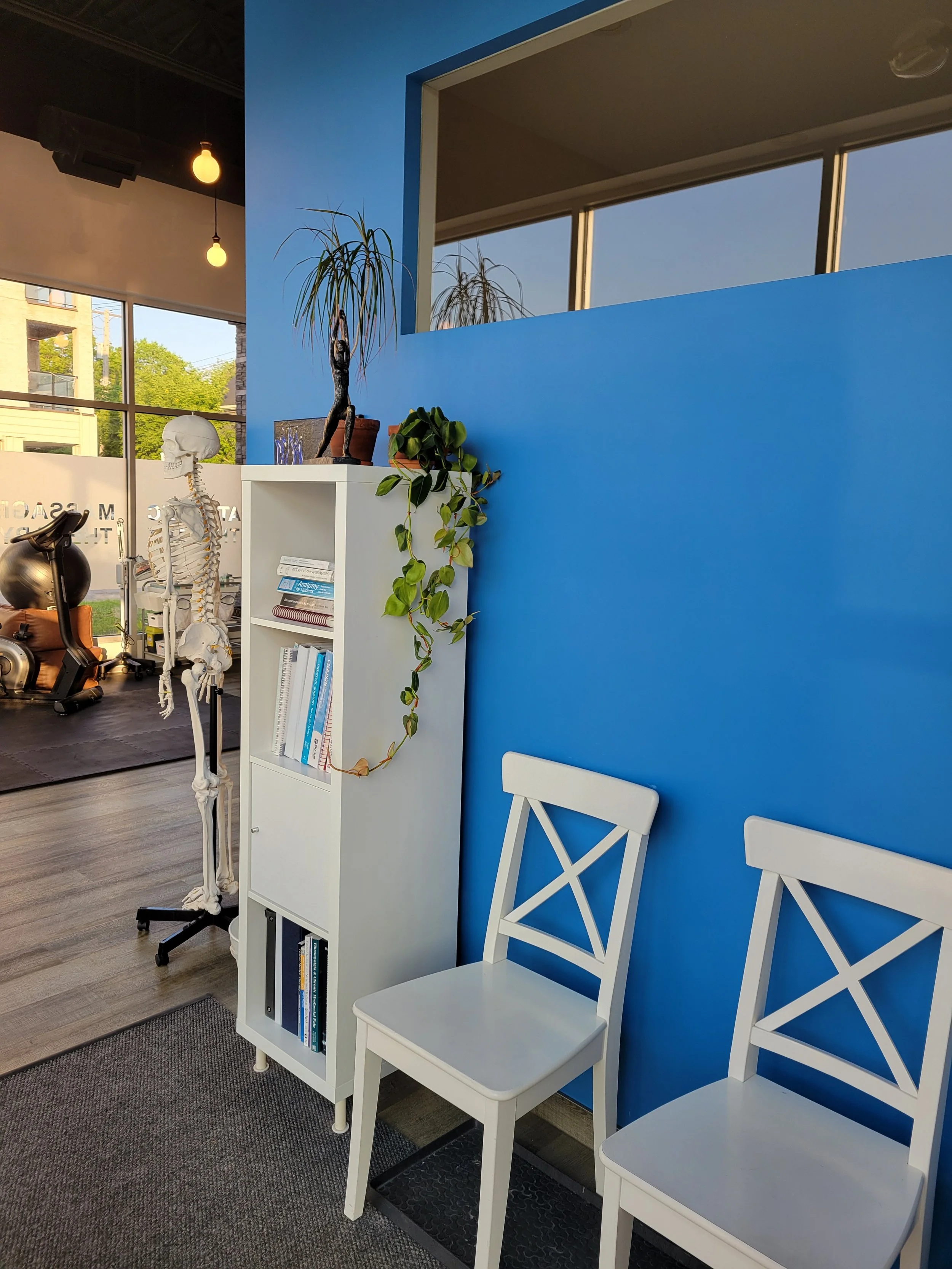 Interior image of a waiting room with blue walls and white chairs in an injury rehabilitation clinic in Winnipeg.
