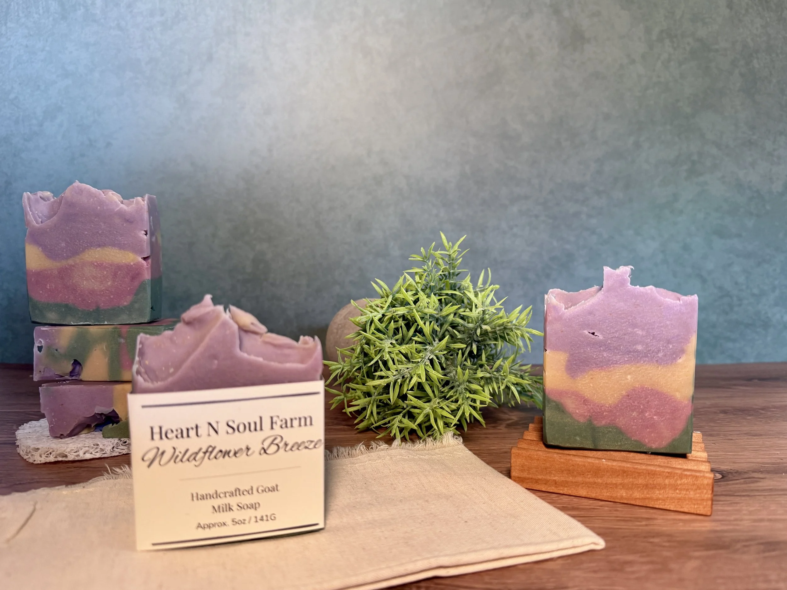 handmade goat milk and lard soap bars that are lavendar, pale yellow, pink and green in color. The label identifies it as Wildflower Breeze.