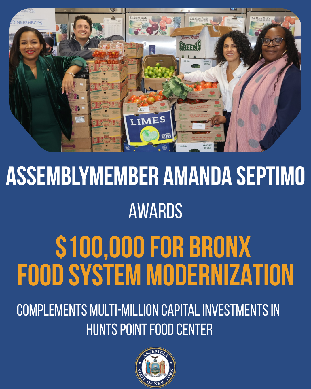 Group of four people standing behind a table filled with boxes of fruits such as tomatoes, limes, and apples, in a food distribution setting.