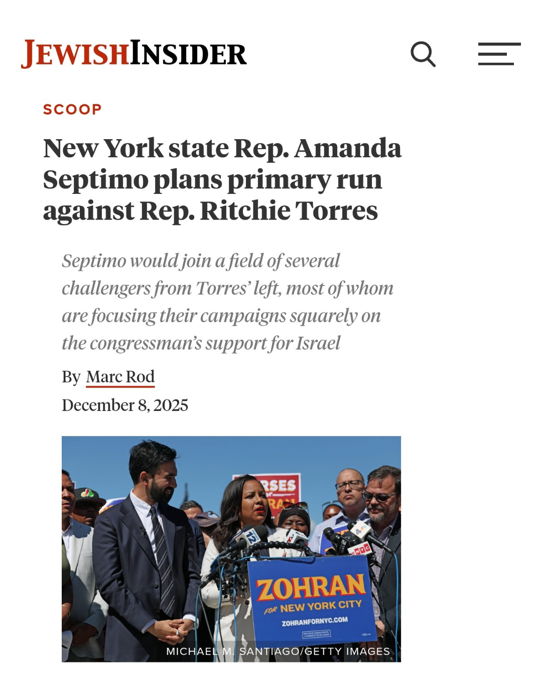 A group of people at a press conference, standing behind microphones and a podium with a blue sign that reads "ZOHRA" and "FOR NEW YORK CITY." Woman speaking into microphone, surrounded by men and women, some wearing sunglasses, against a clear blue 