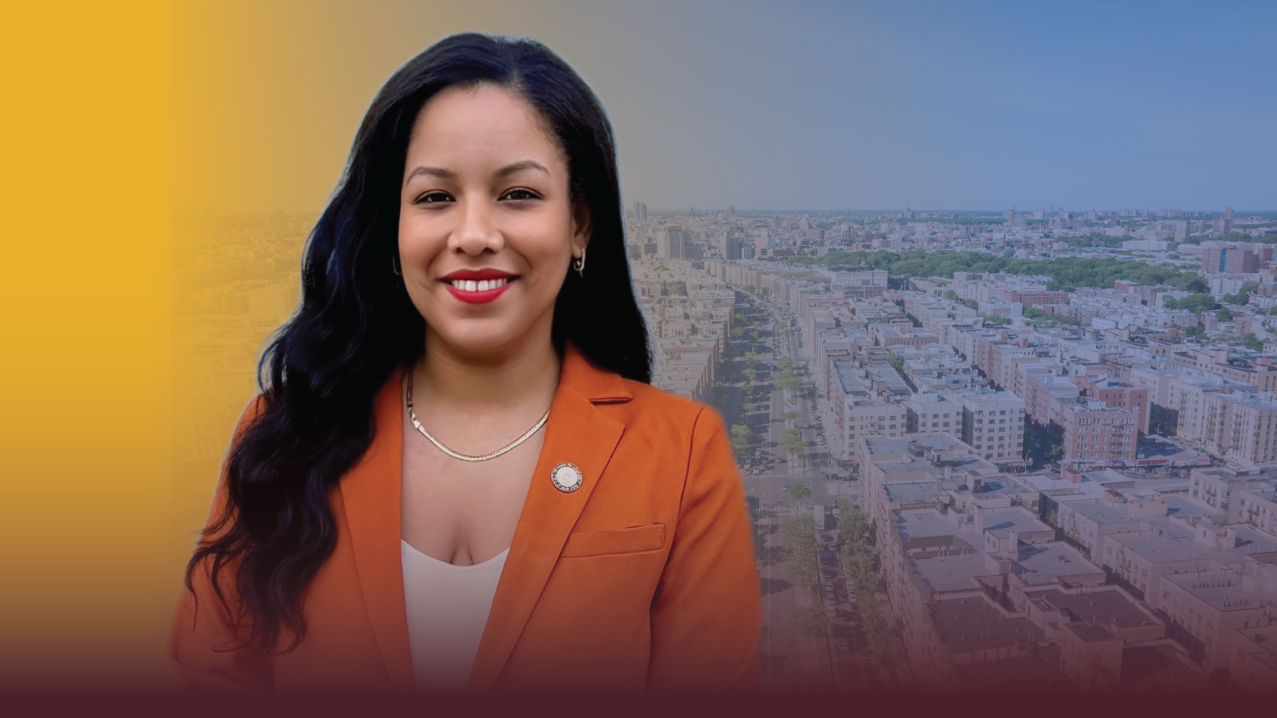 A woman with long dark hair, wearing an orange blazer and smiling, standing in front of an aerial view of a cityscape with residential and commercial buildings.