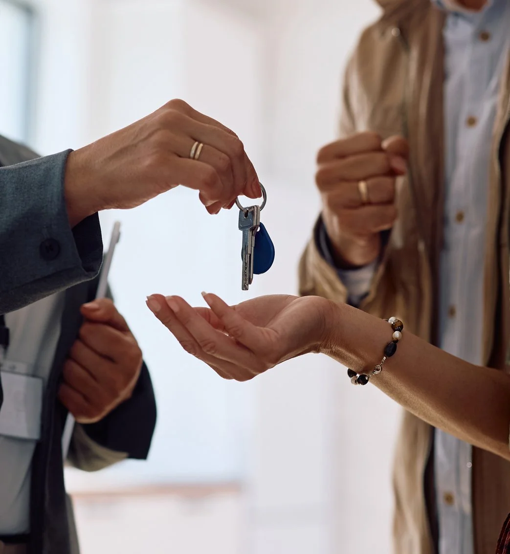 Person handing over a key to another person, possibly at a rental or sales transaction.