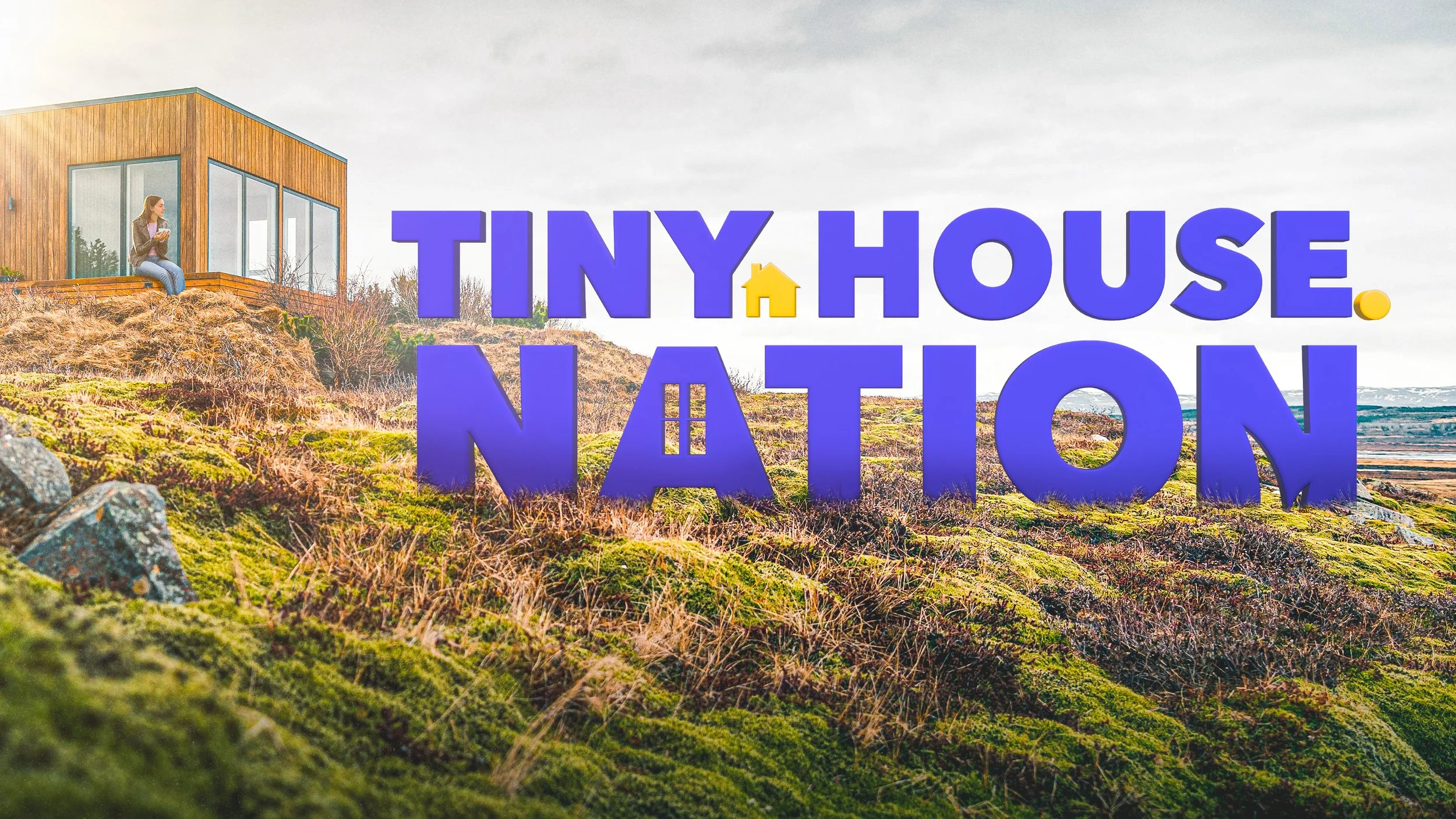 A woman sitting on a wooden deck outside a modern tiny house with large glass windows, surrounded by a grassy, rocky landscape. Large purple and yellow sign reads 'Tiny House Nation'.