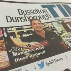 A newspaper or magazine page featuring a man holding a mobile phone or similar device, with headlines about Bussleton Dunsborough and a call for members to help those in need.