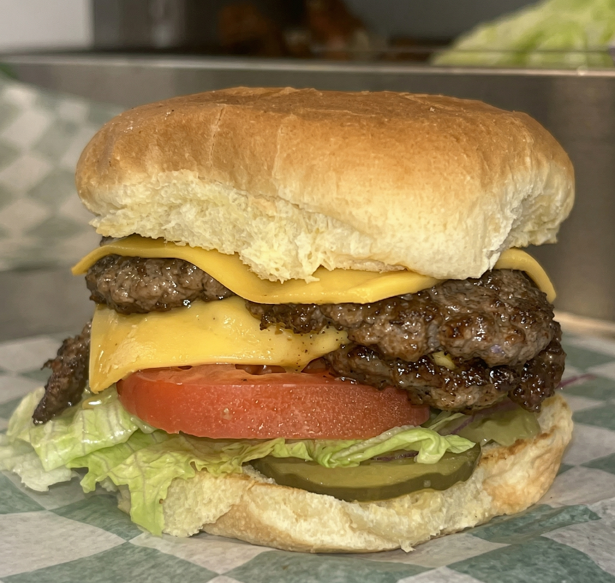 Close-up of a cheeseburger with lettuce, tomato, pickles, cheese, beef patty, and a sandwich bun.