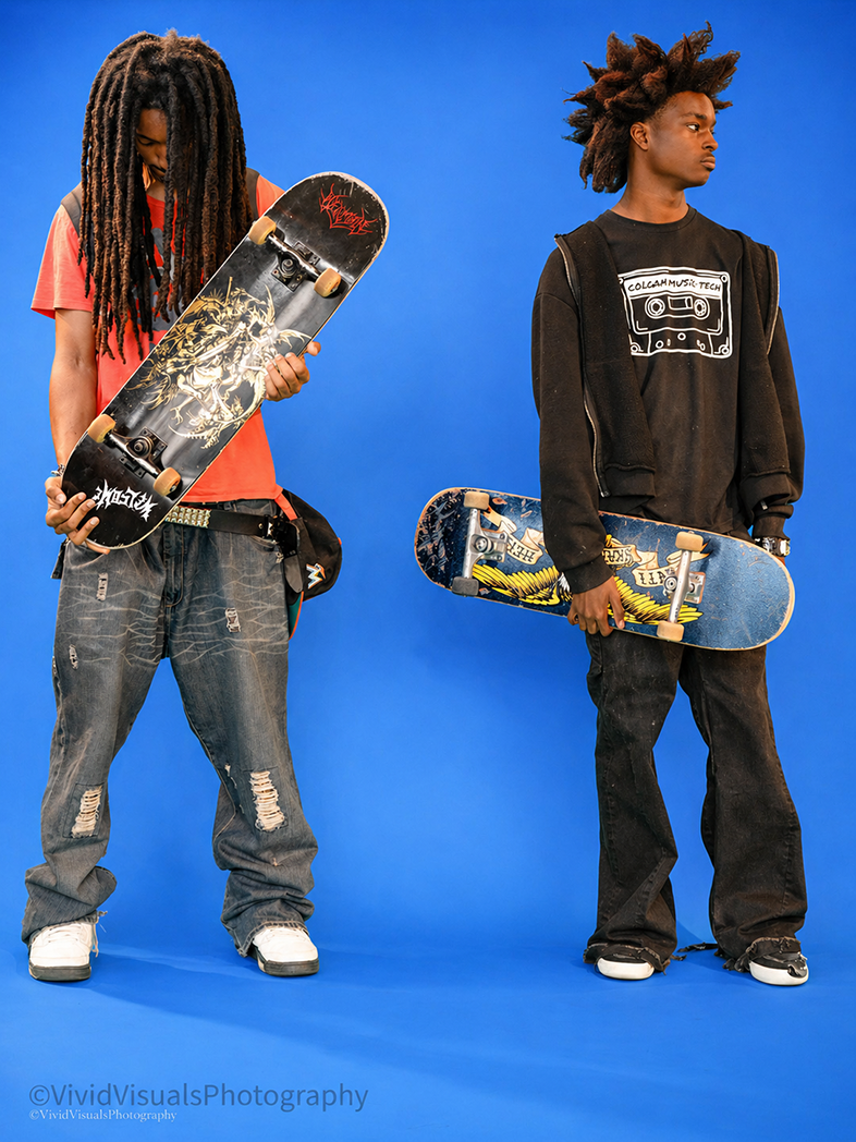 Two young men with dreadlocks holding skateboards against a blue background.