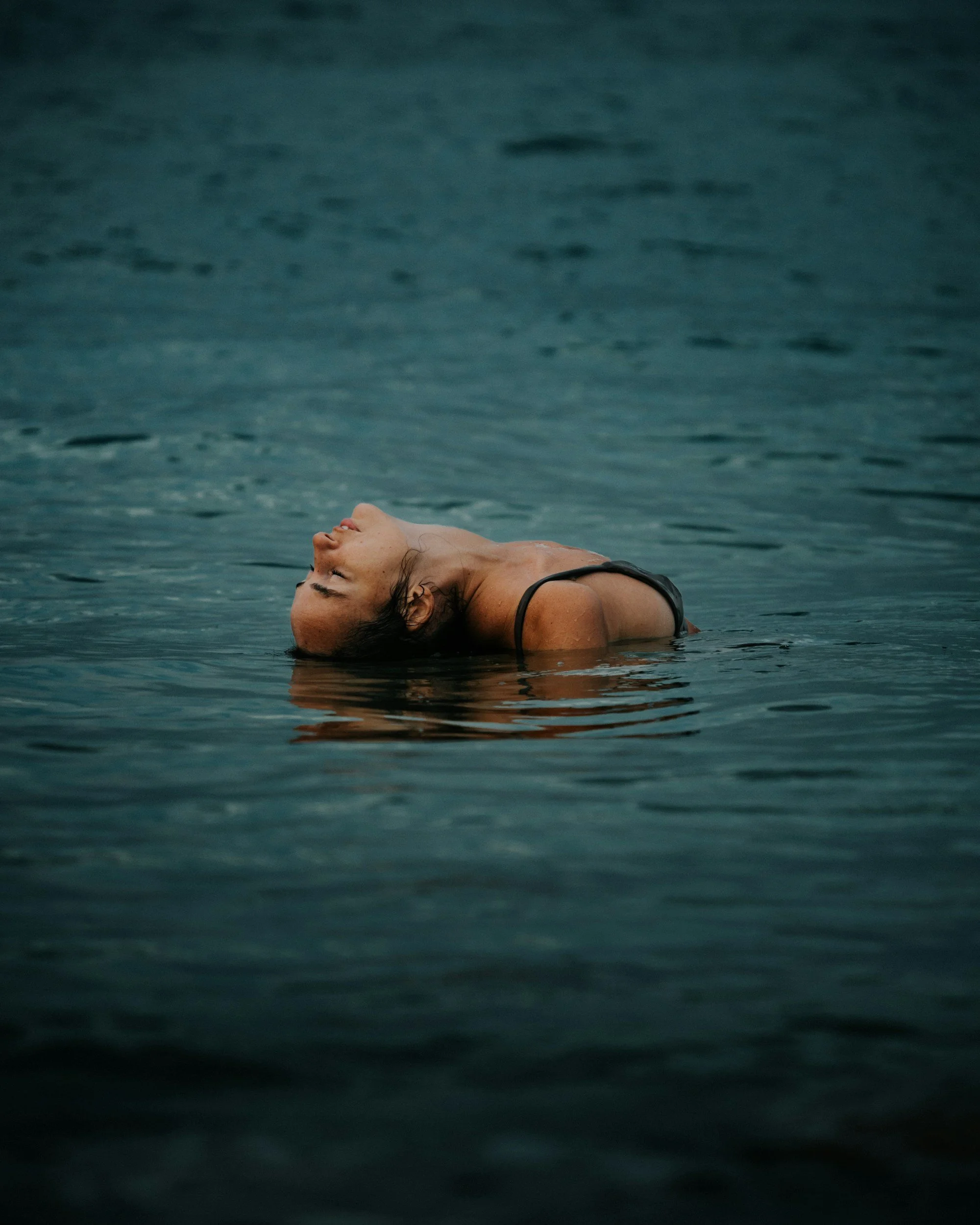 Woman floating on her back in water with her eyes closed and head tilted back.