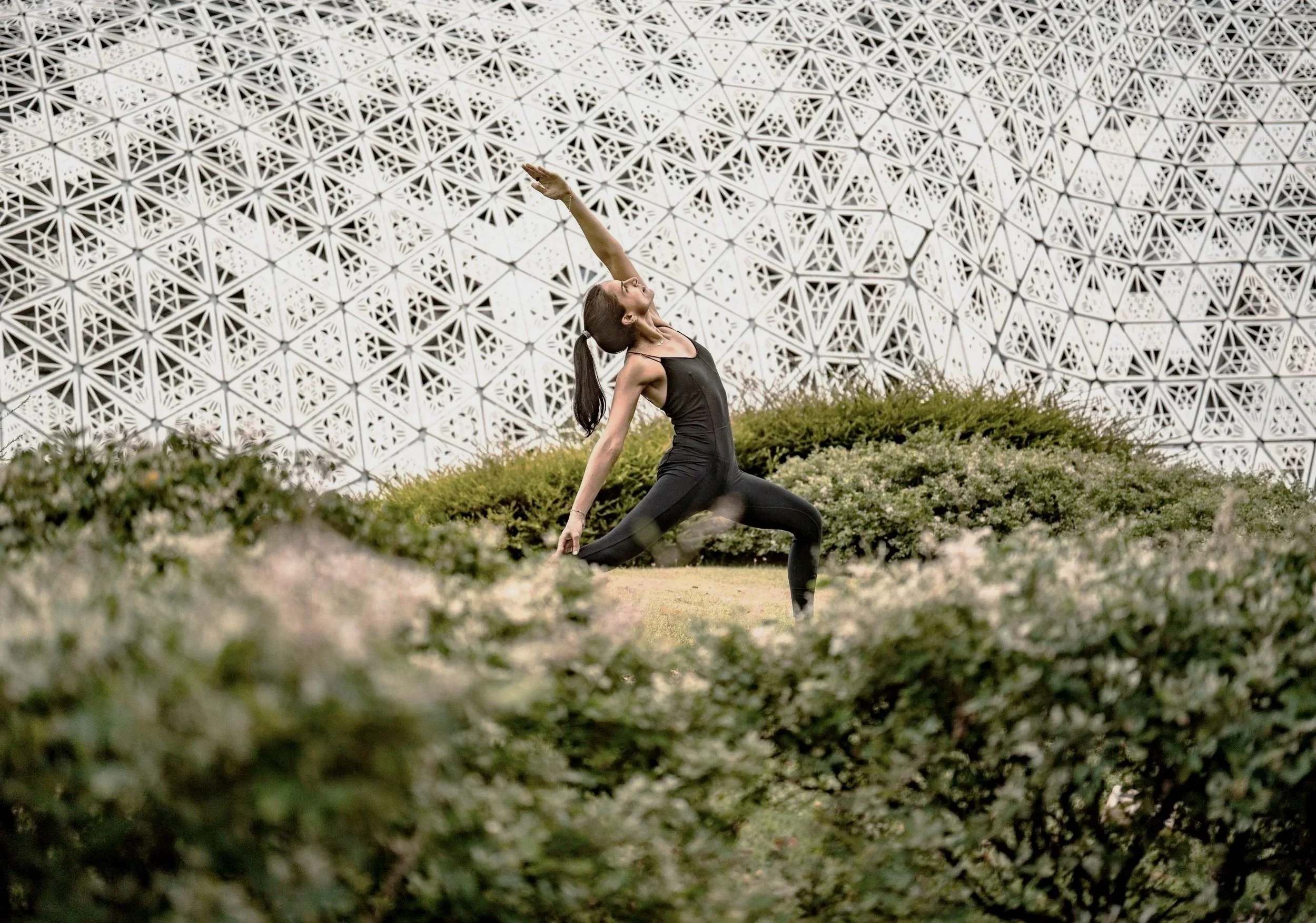 A person practicing dynamic yoga movement against contemporary architectural forms.