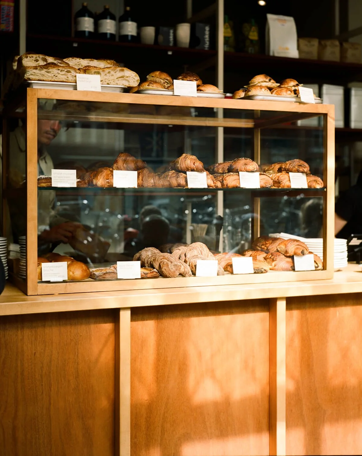 Display case with various pastries including croissants, bread, and scones in a bakery.