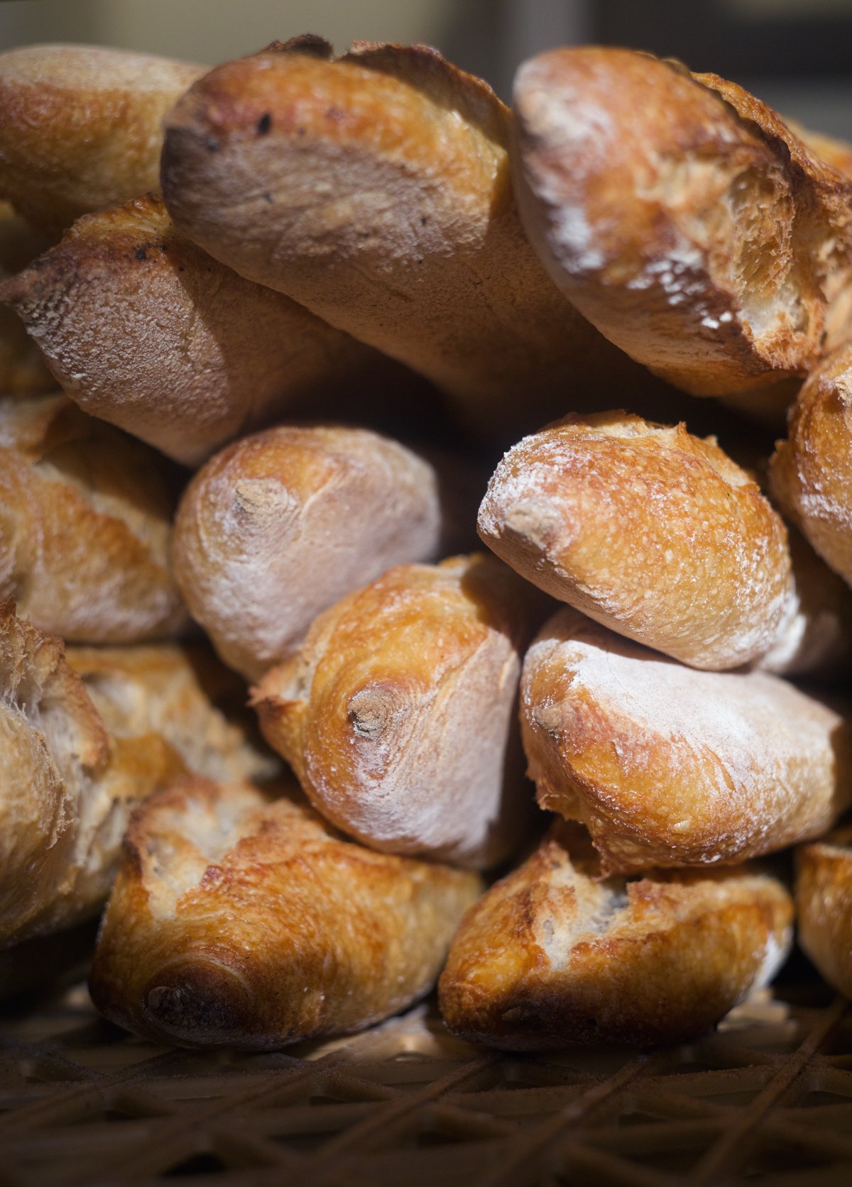 Close-up of a pile of bread rolls with a golden-brown crust and light dusting of flour.