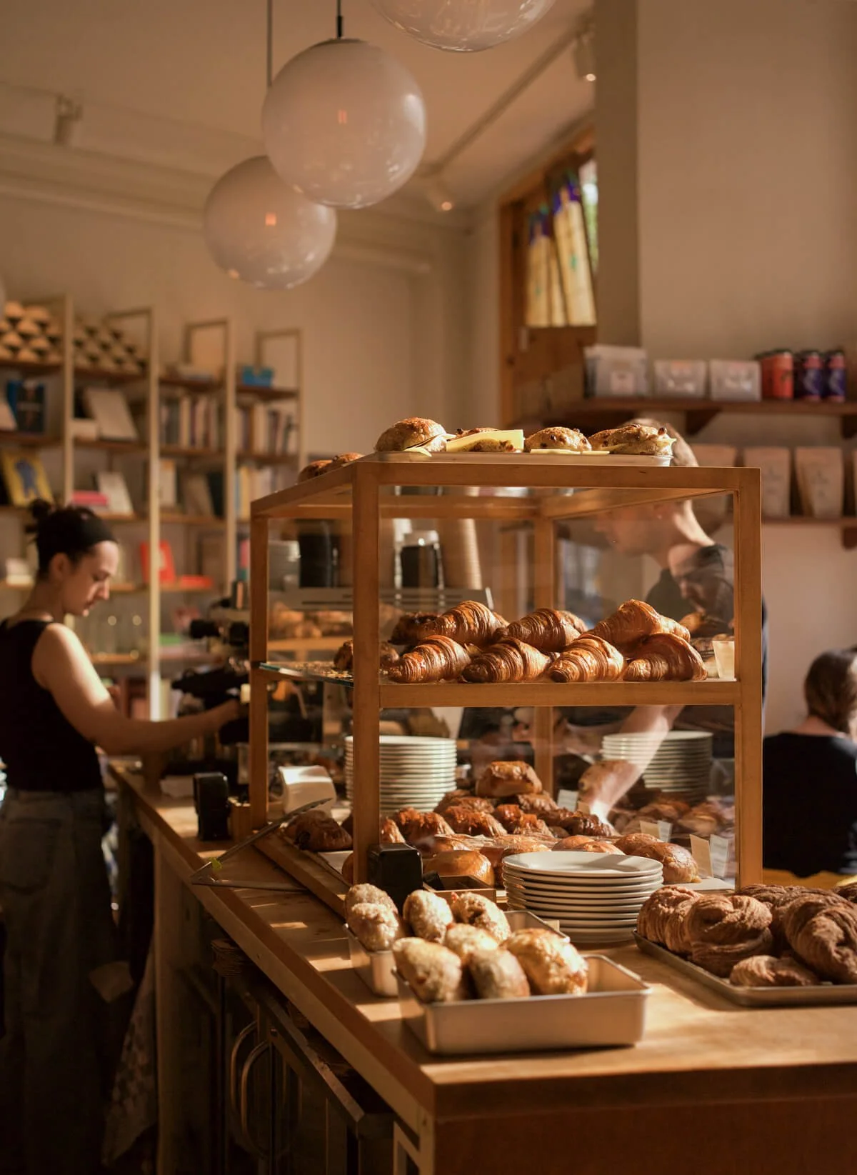 Display case with croissants, muffins, and scones in a cozy bakery or cafe.