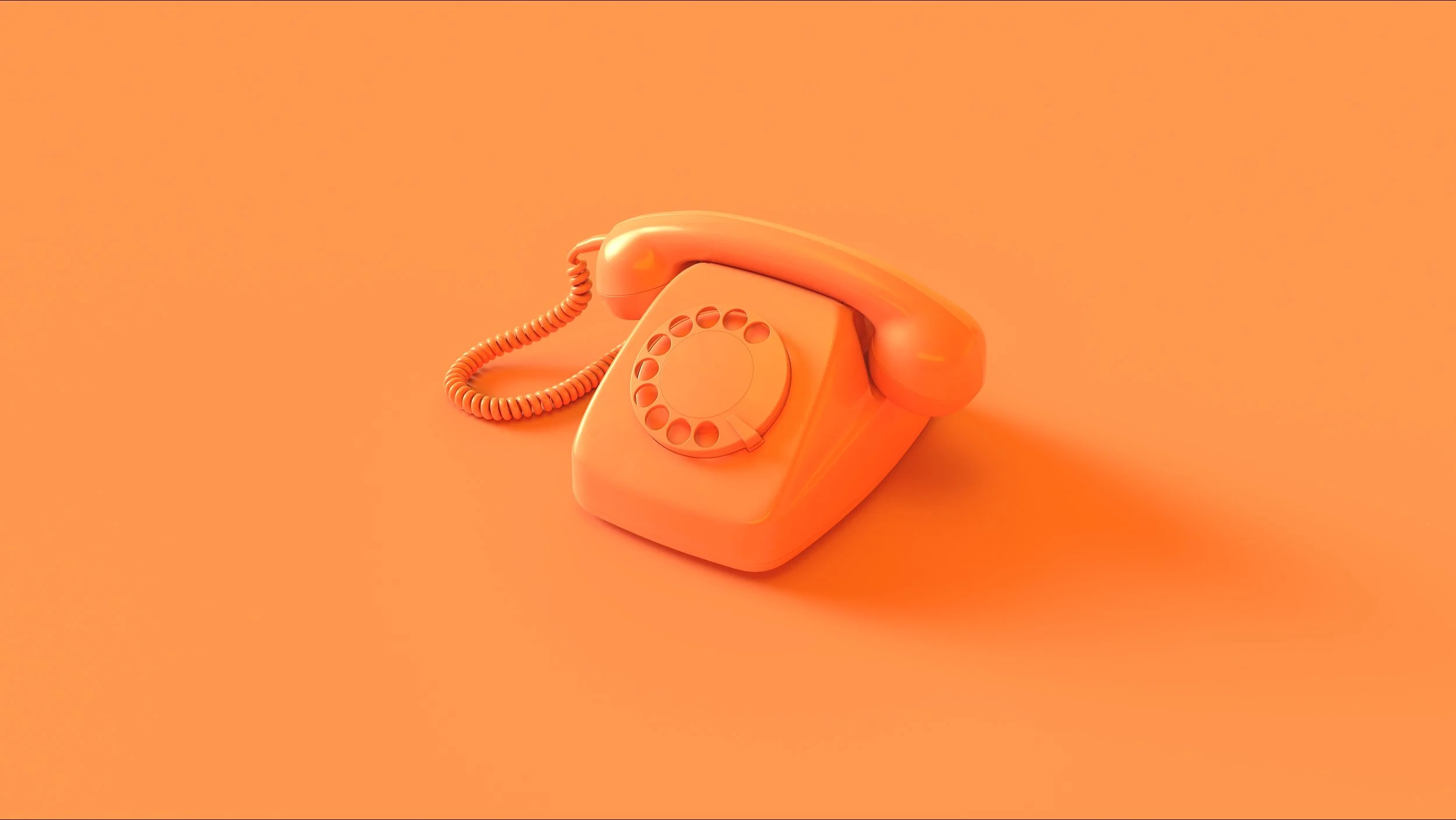 An orange vintage rotary telephone placed on an orange background.