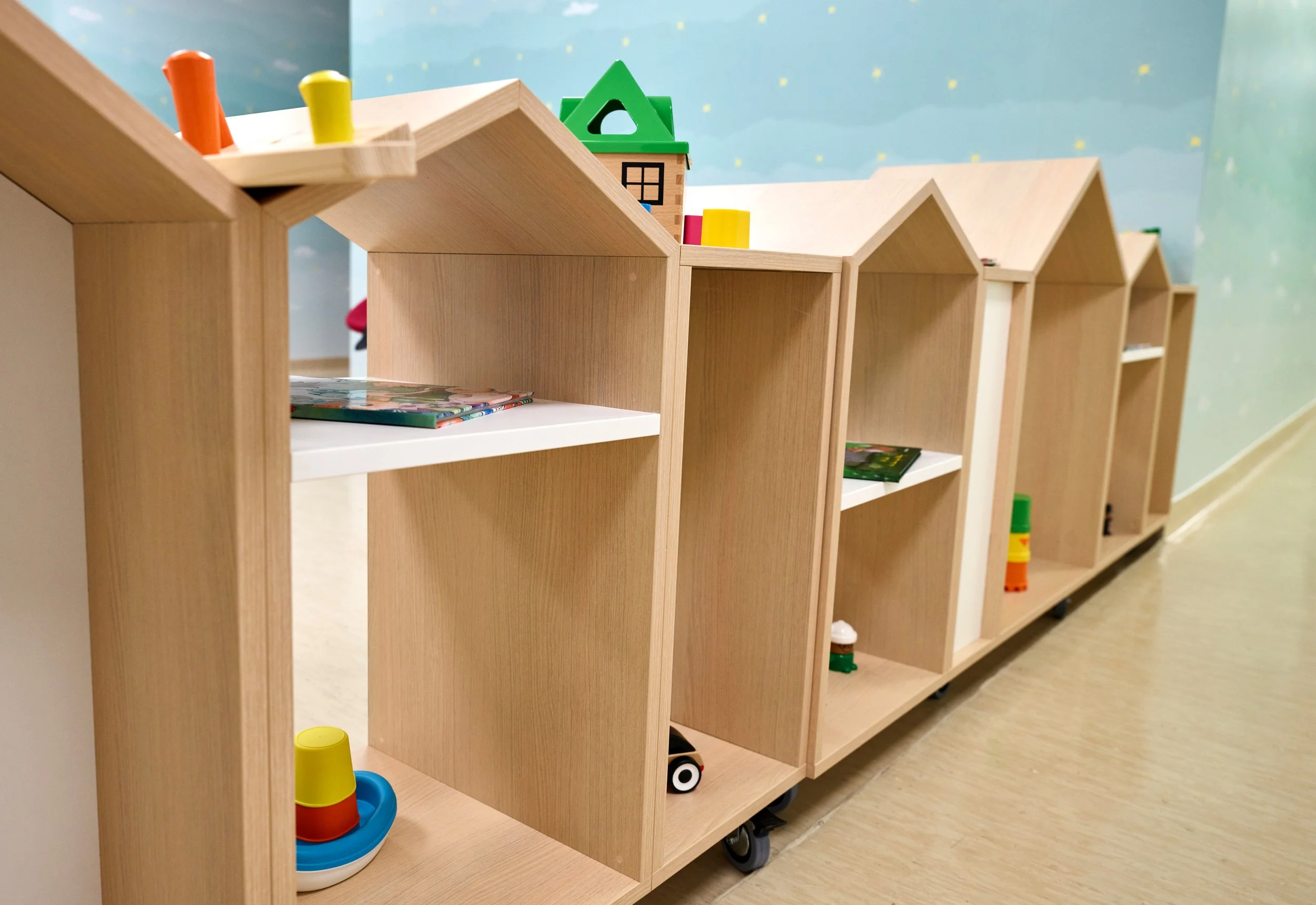 Child-sized wooden bookshelves with toys and books in a children's play area.