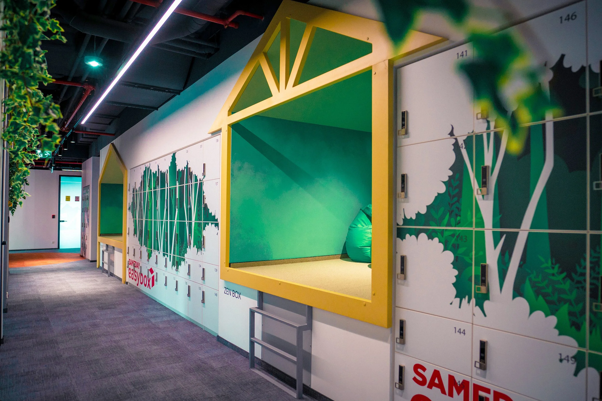 Indoor hallway with locker unit designed as a bamboo-themed storage with a green Zen box and a cozy seating area, illuminated by modern ceiling lights.