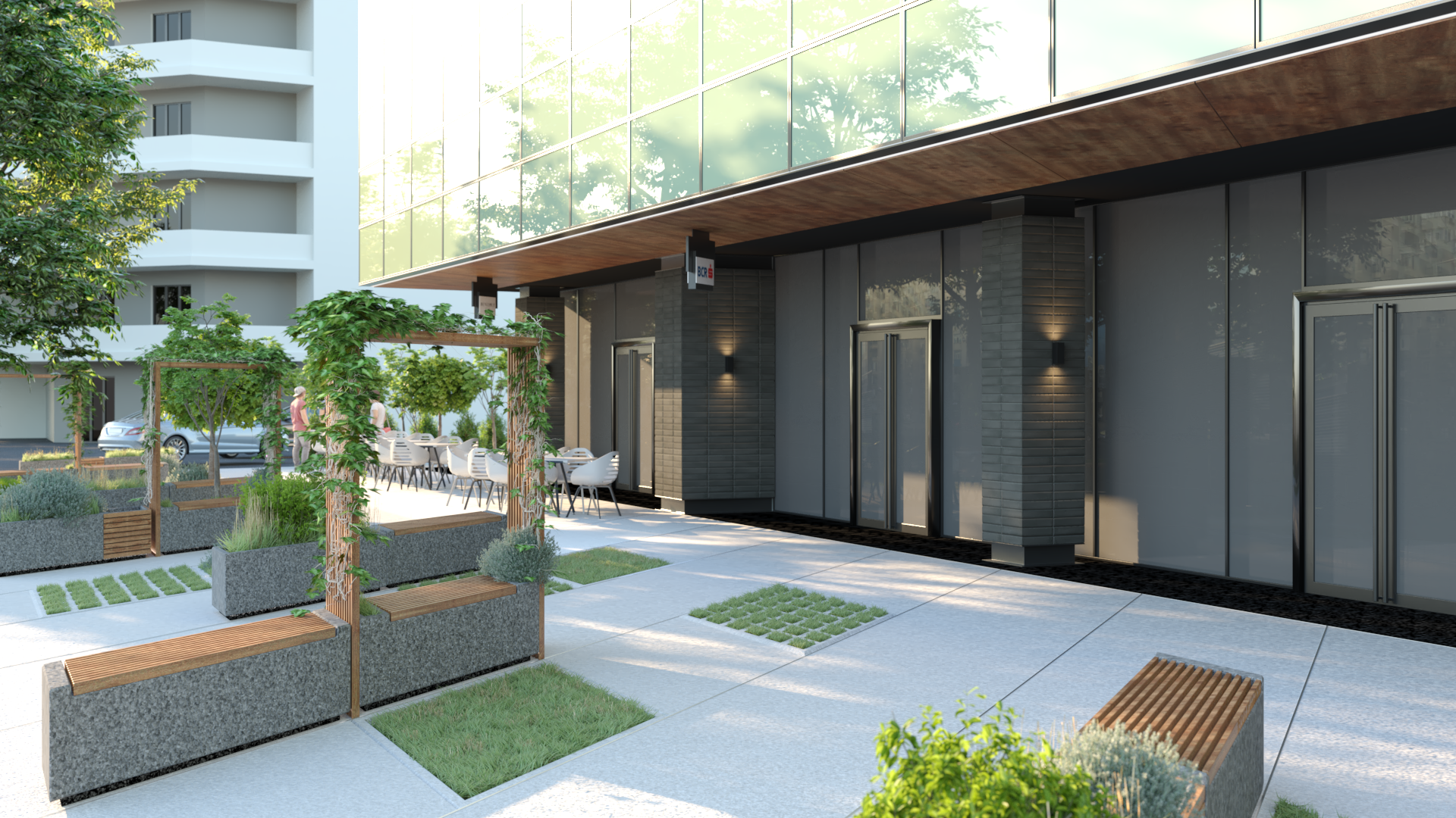 Modern outdoor patio area with seating, greenery, and plants, adjacent to a contemporary building with large glass windows.