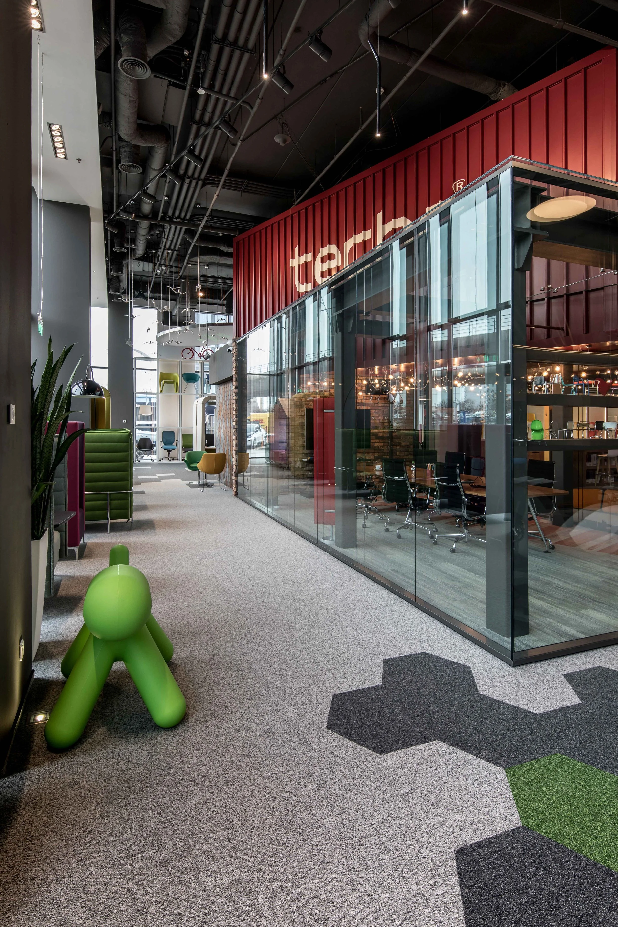 Interior of a modern office or showroom with colorful chairs and a glass-enclosed meeting room.