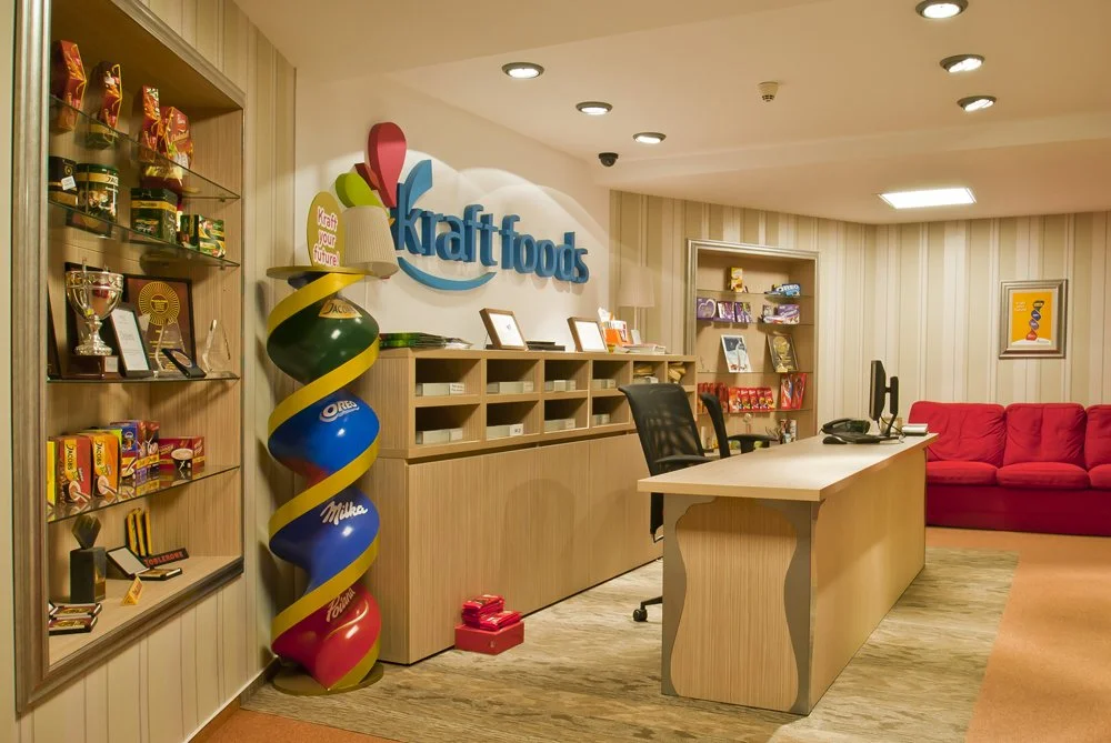 Kraft Foods office reception area with shelves of products, awards, a desk with two monitors, and a red sofa in the background.