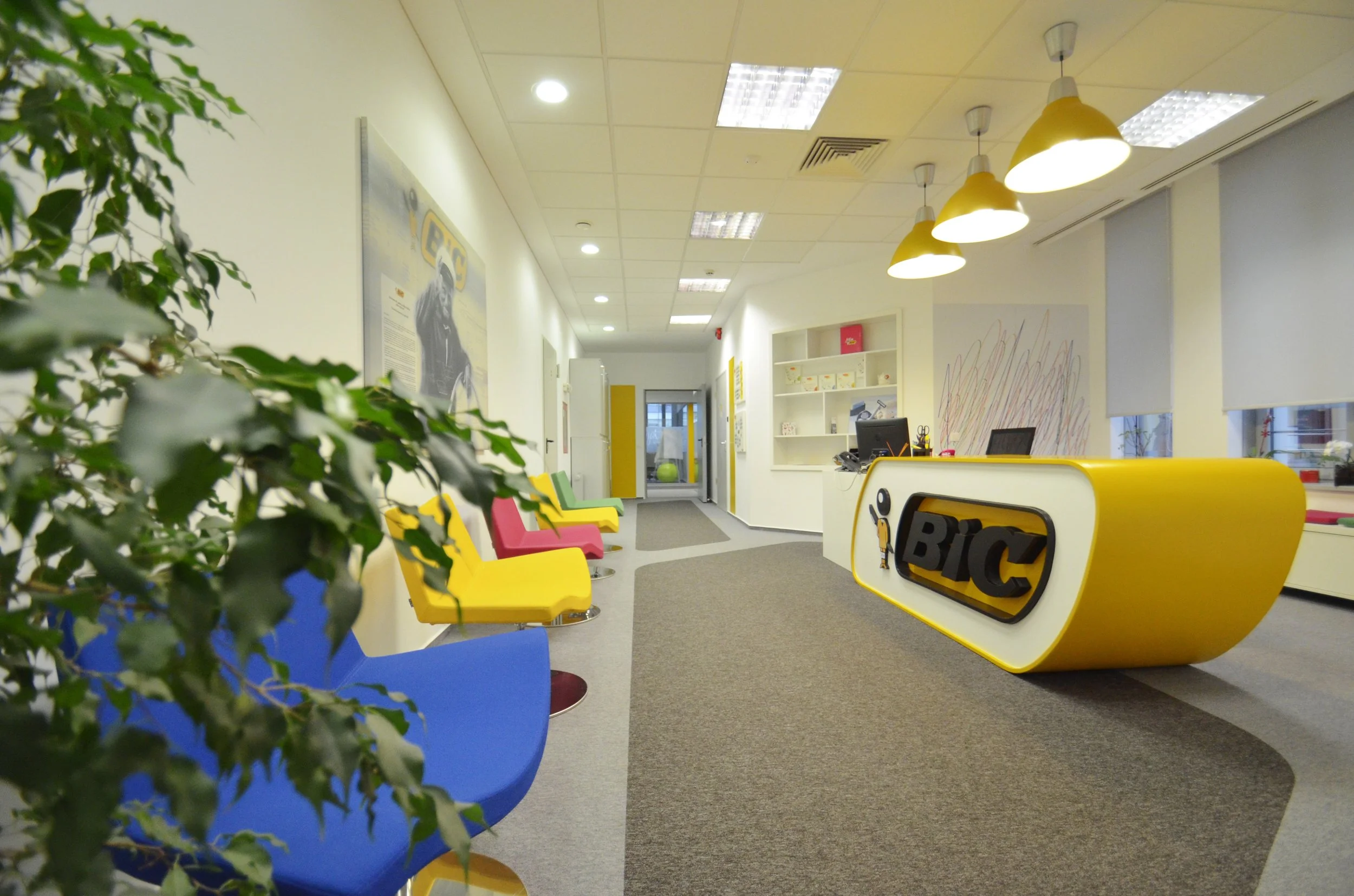 An office lobby with colorful chairs, a reception desk with the BIC logo, and modern decor.